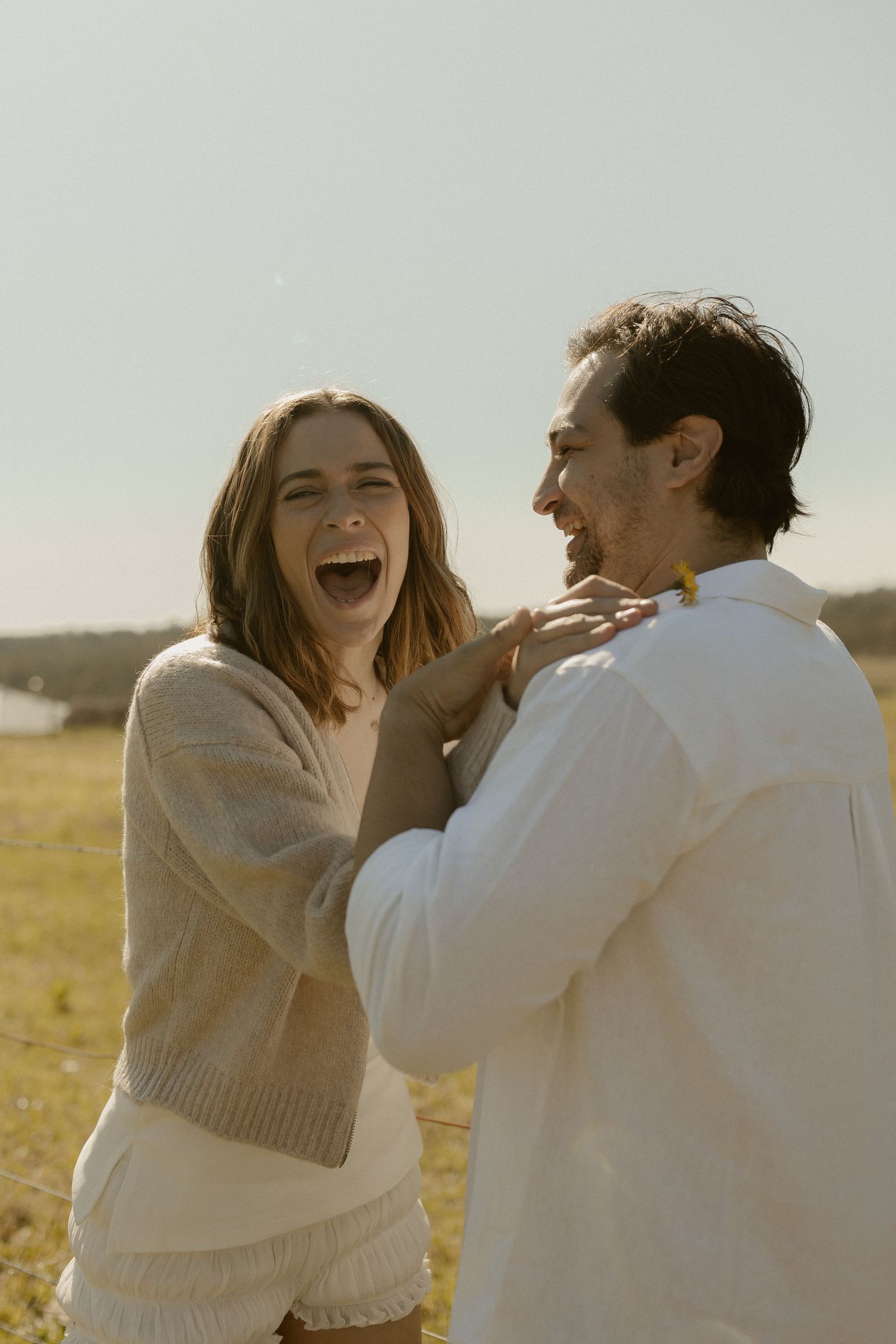 Carefree moments shared between two people laughing together in a sunny field.