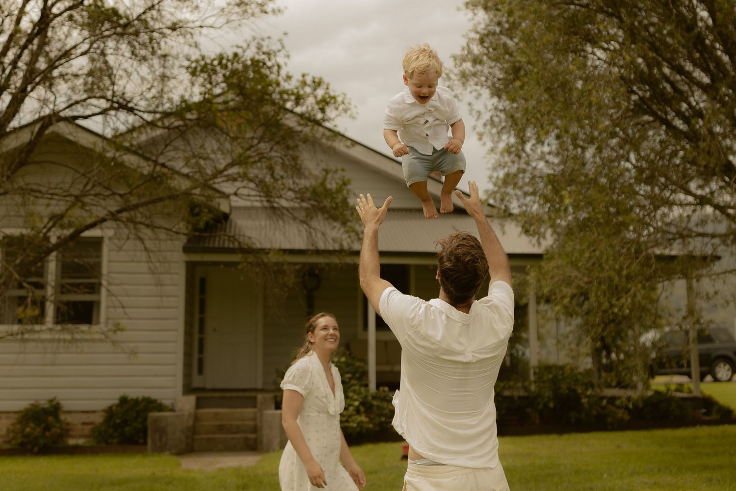 A playful outdoor scene in a grassy field with white clothing and joyful movement.