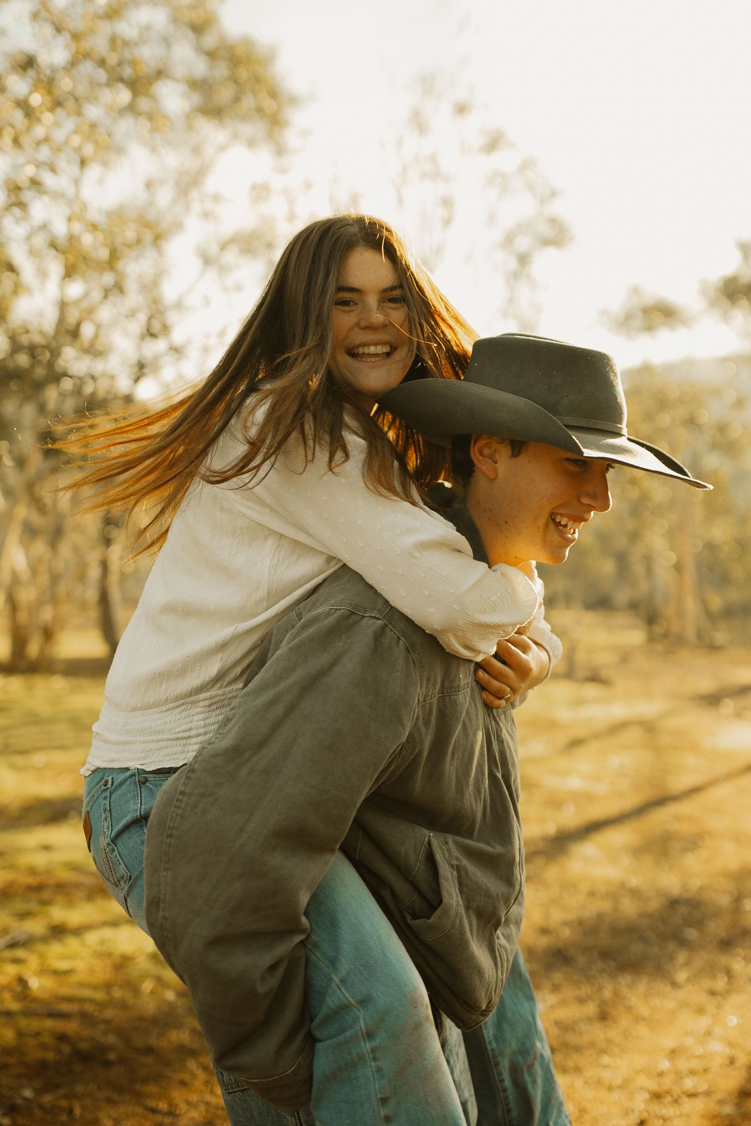 A joyful piggyback ride moment captured in warm sunlight on a country path amongst trees.
