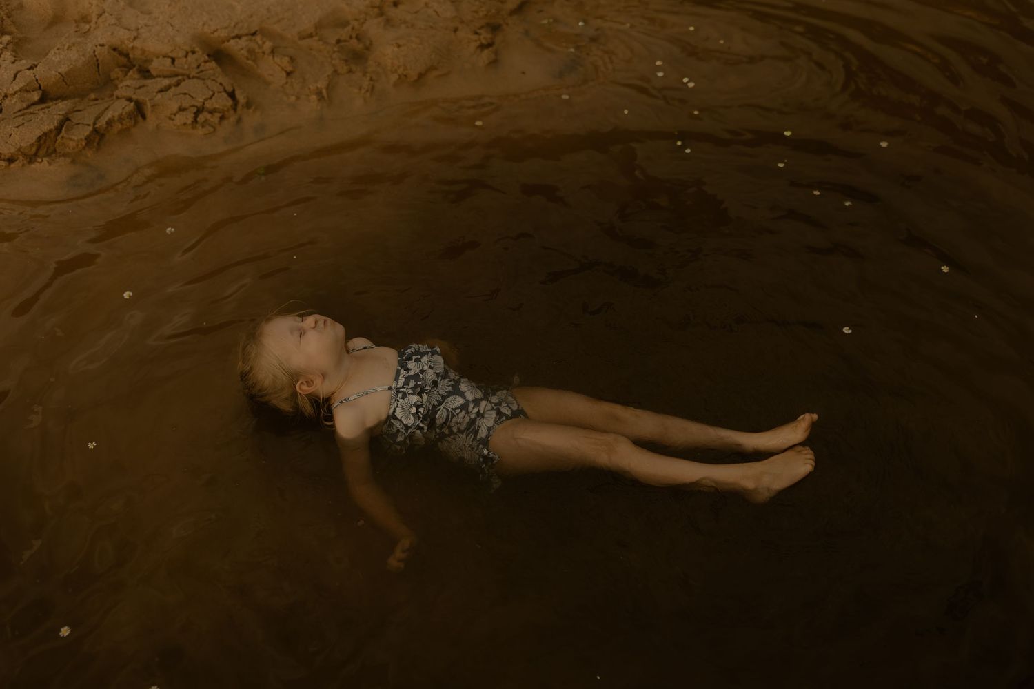 Person floating peacefully in dark water creating a serene and moody atmosphere.