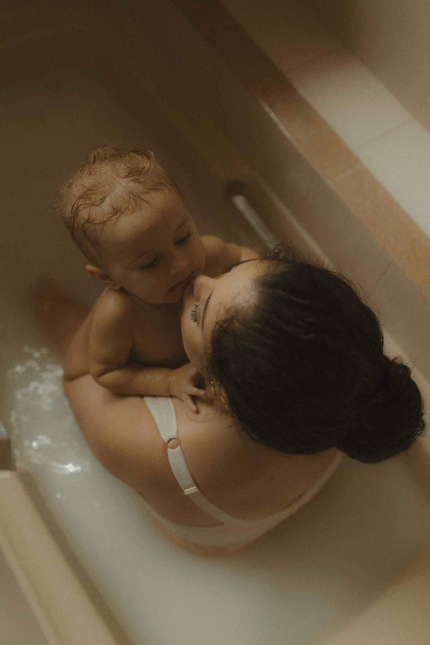 A series of four connected photos showing someone relaxing in a bathtub filled with water.