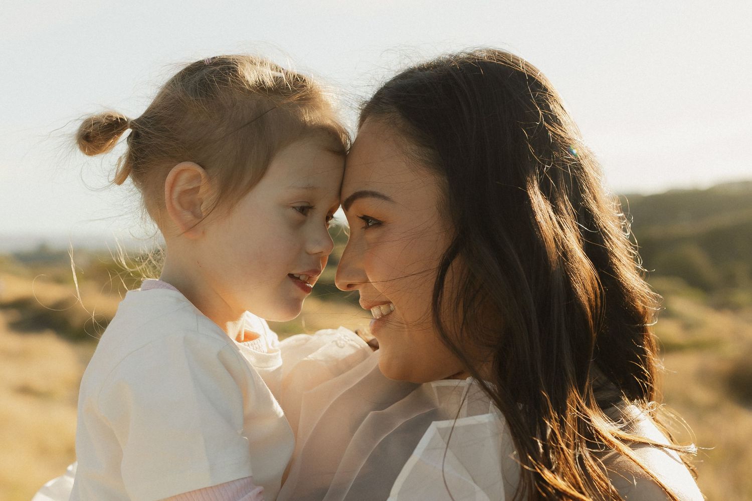 A close and tender moment between parent and child at sunset in a desert landscape.