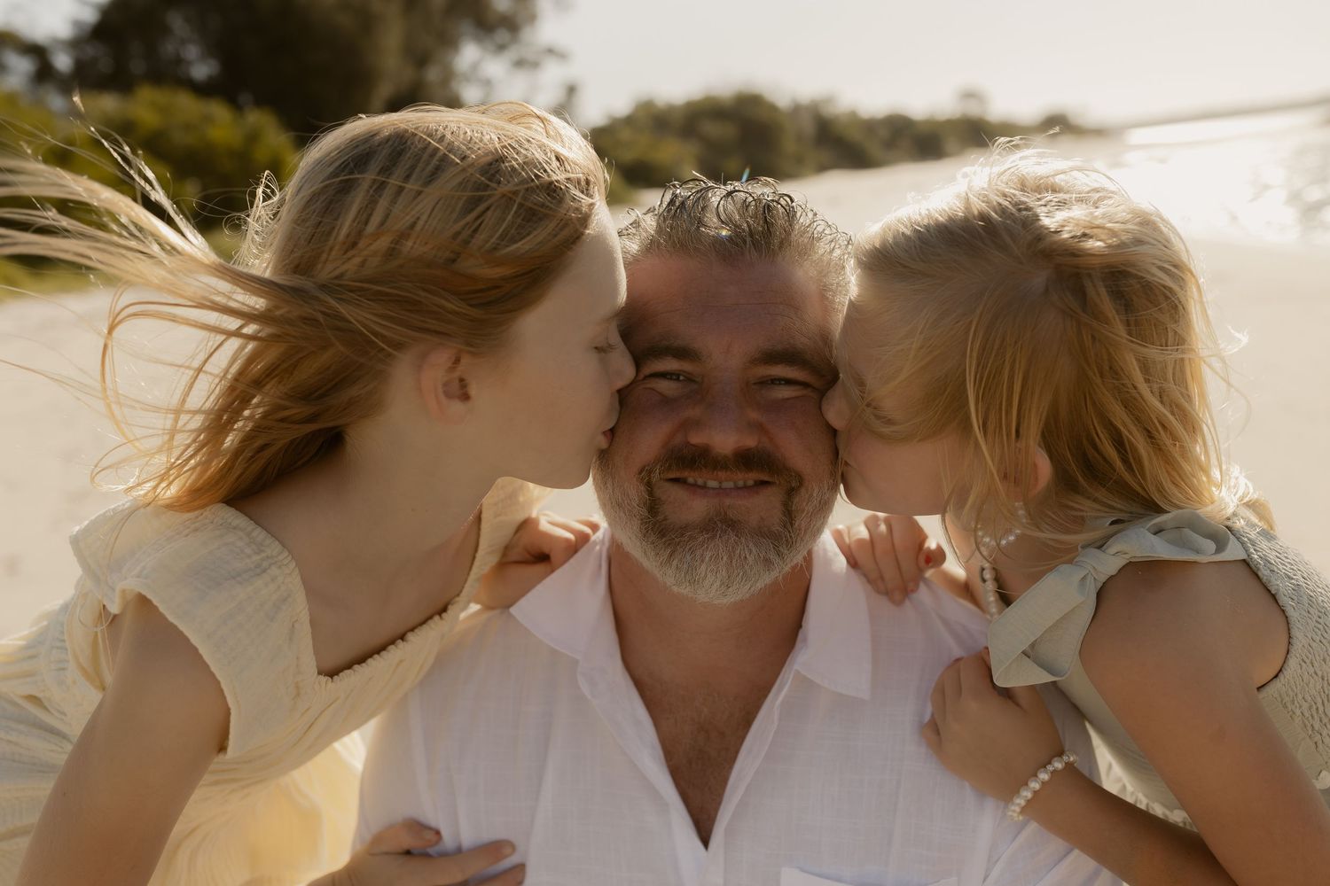 Playful family moment captured at sunset on a beach with warm golden lighting.