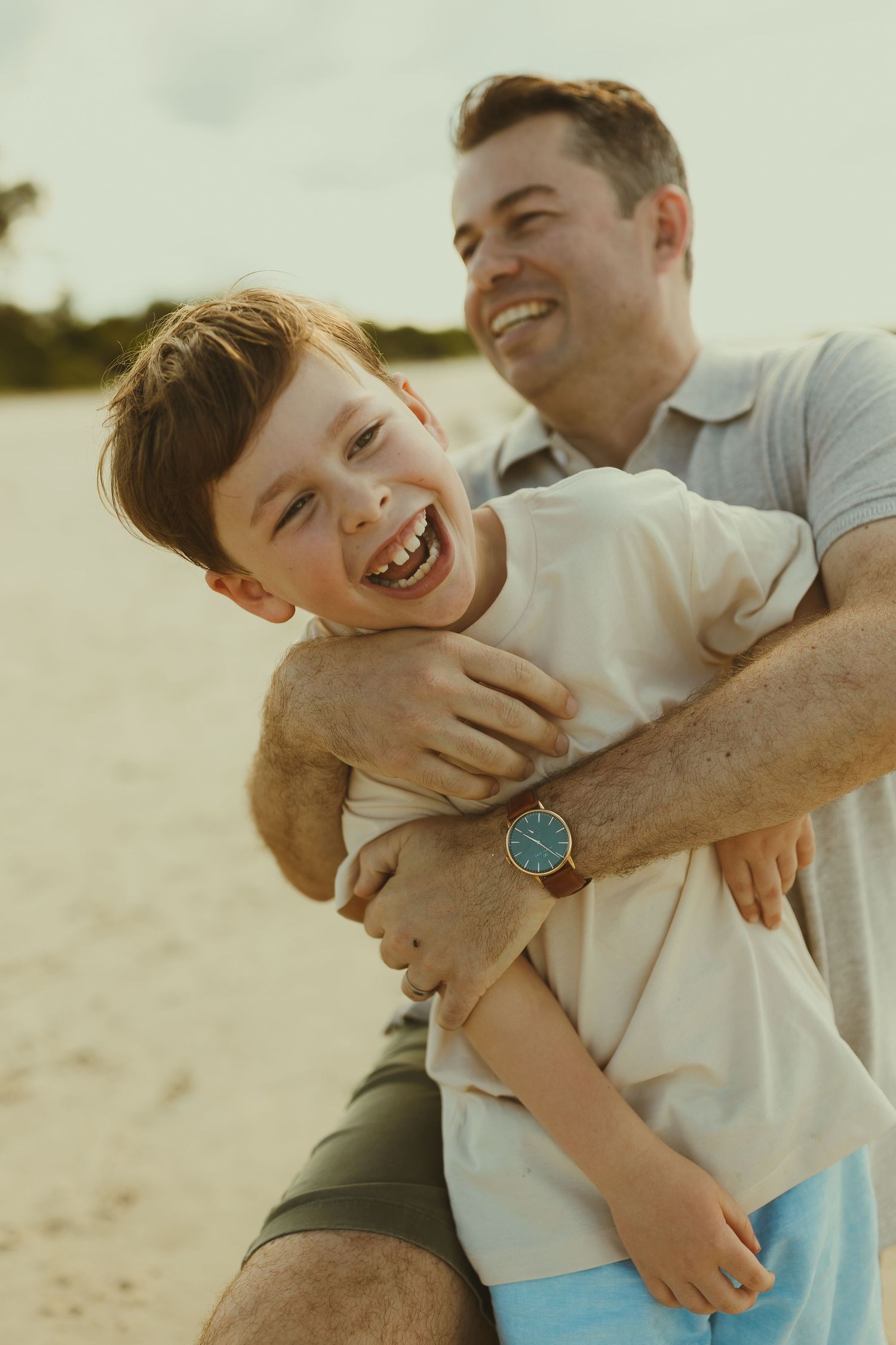 A joyful moment of play and laughter between parent and child on a sunny beach.