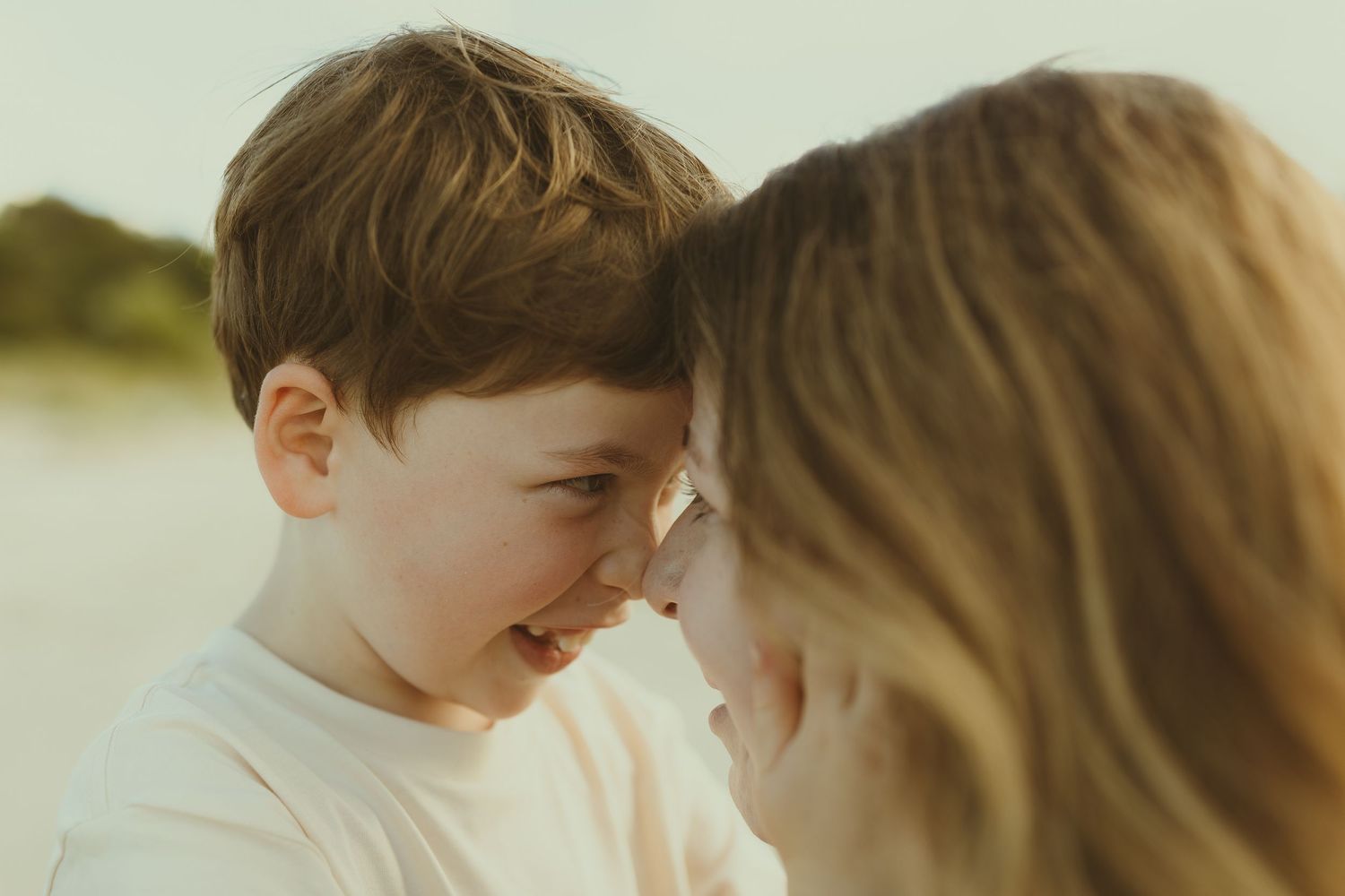 A tender moment between parent and child as they touch foreheads together in soft natural lighting.
