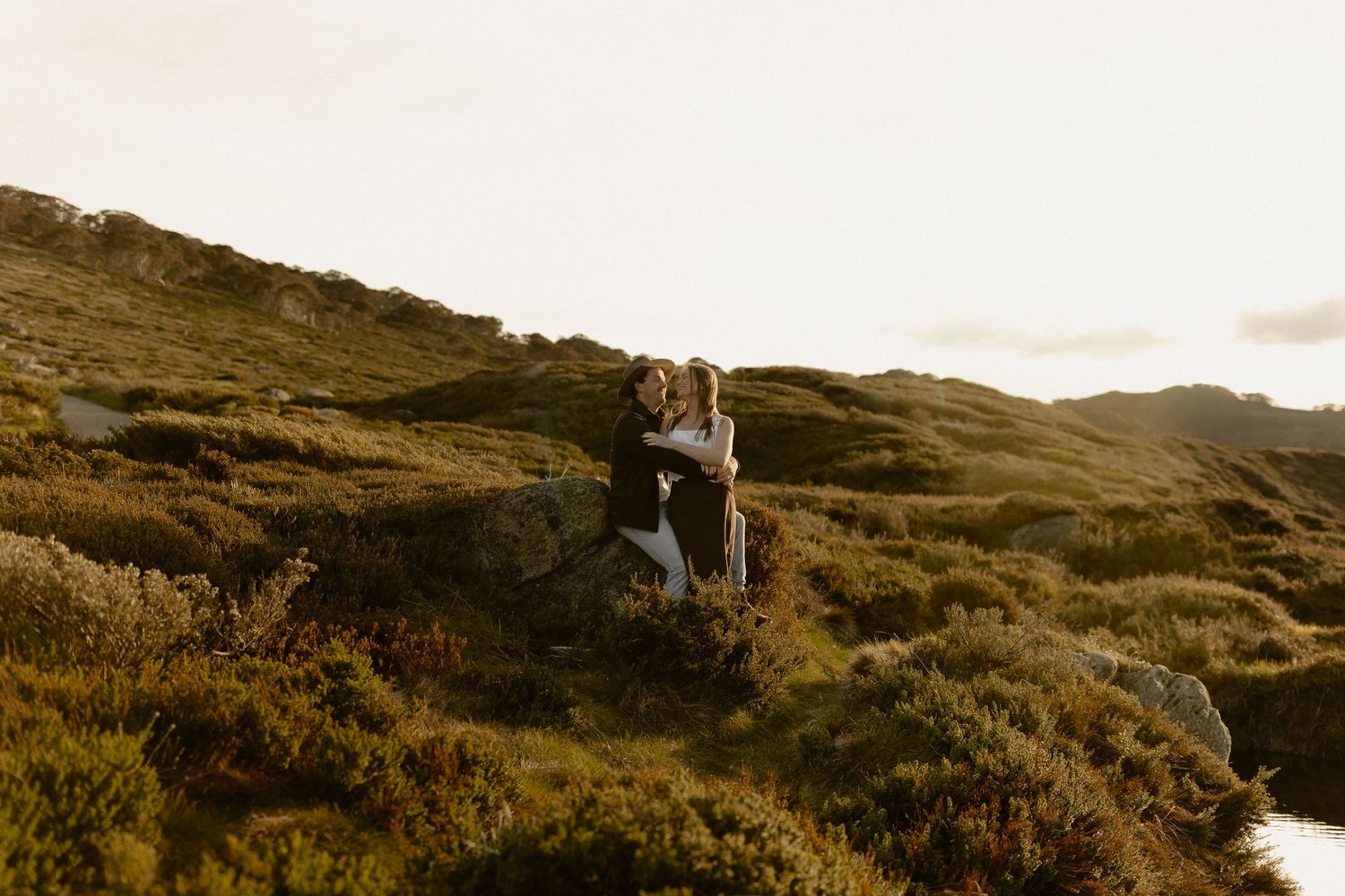 A scenic mountain landscape at sunset with rugged peaks and golden light illuminating the rocky terrain.