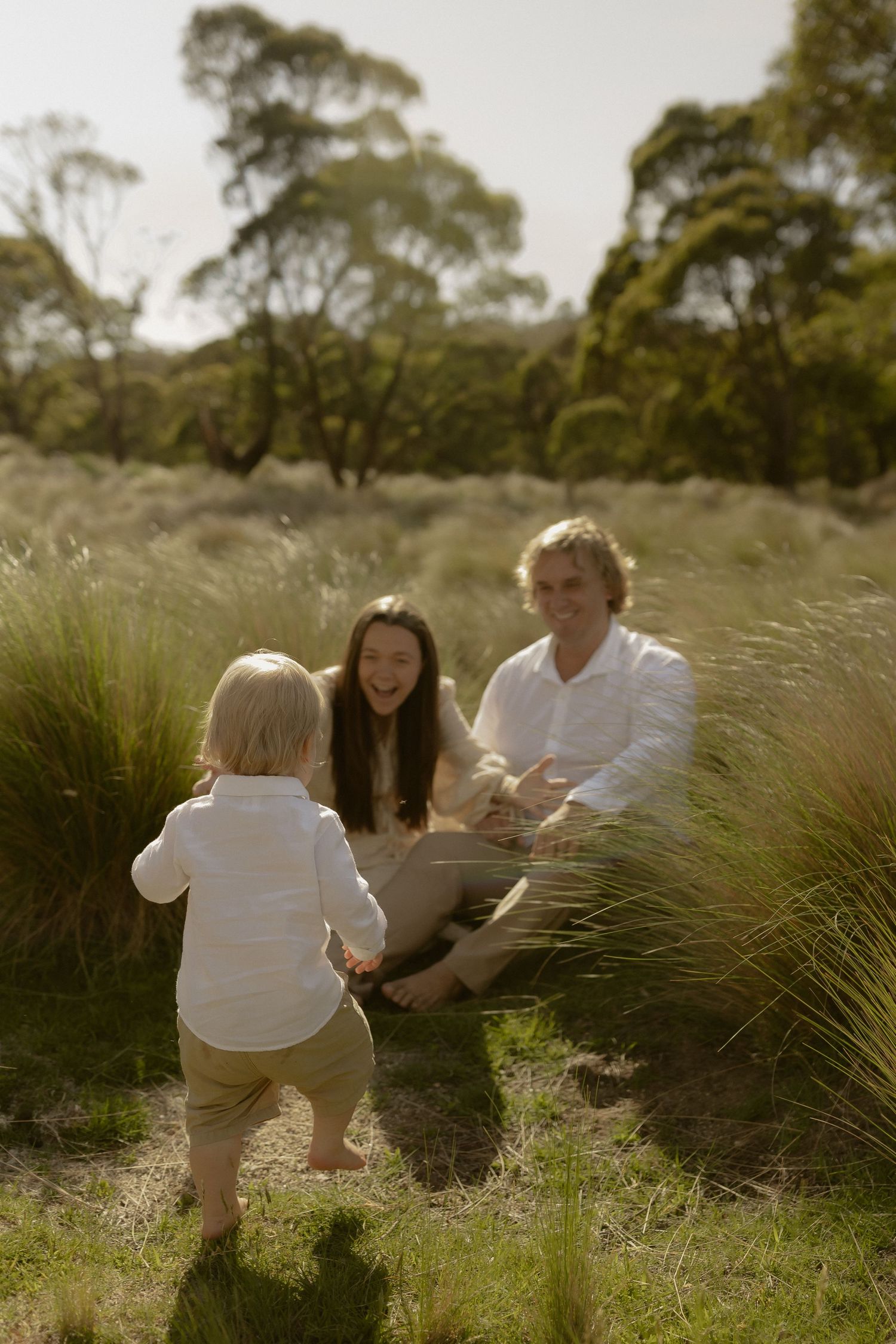 Family enjoying a sunny afternoon together outdoors among tall grass and natural scenery.