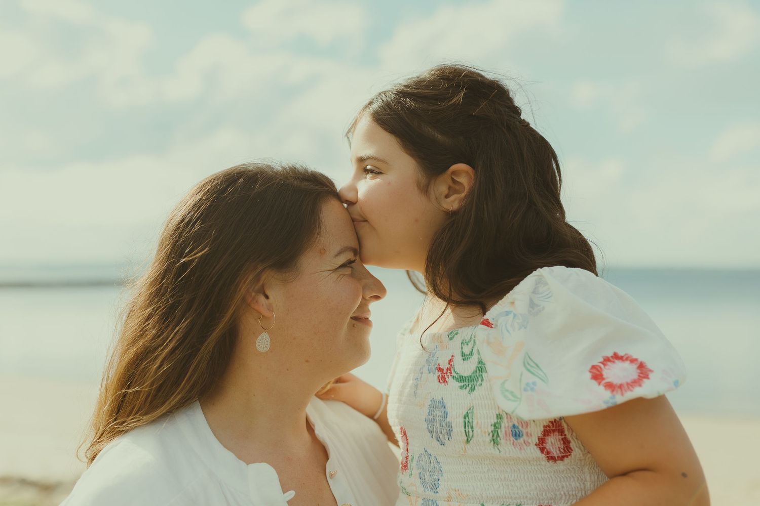 An intimate moment between two people sharing affectionate gestures on a sunny beach.
