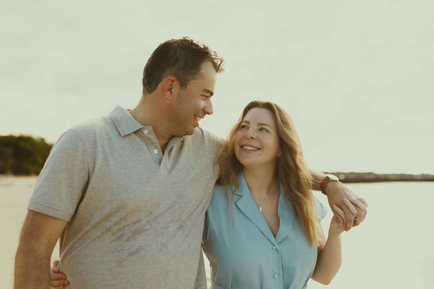 Couple sharing a joyful moment together while walking on a beach at sunset.