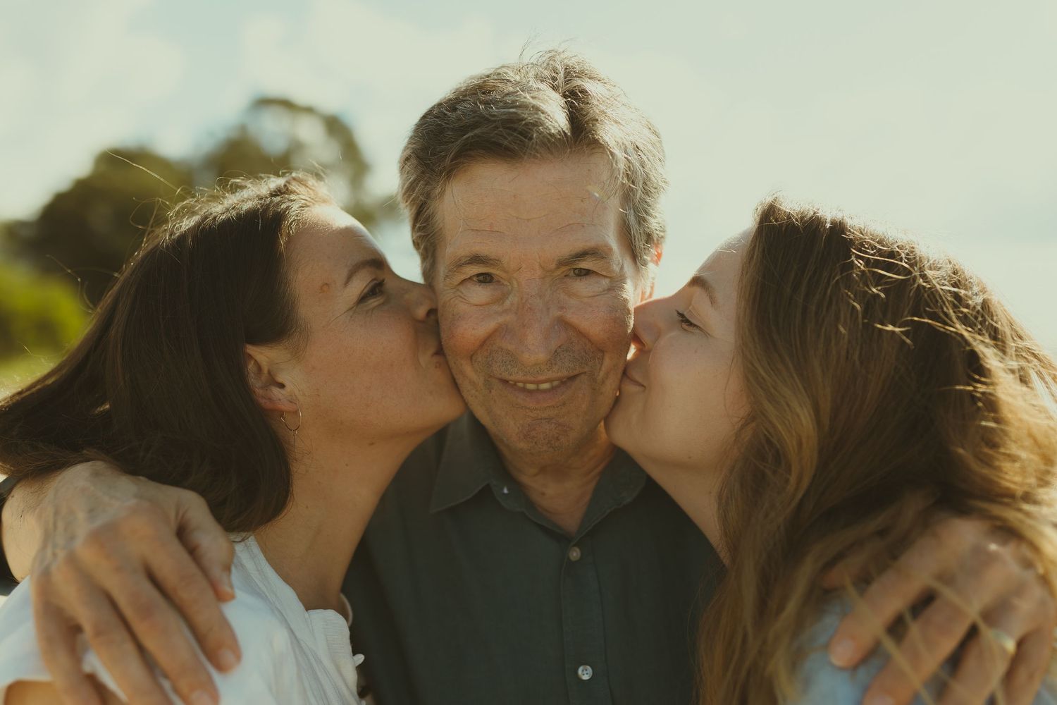 A series of five connected photos showing affectionate family moments in warm sunlight outdoors.