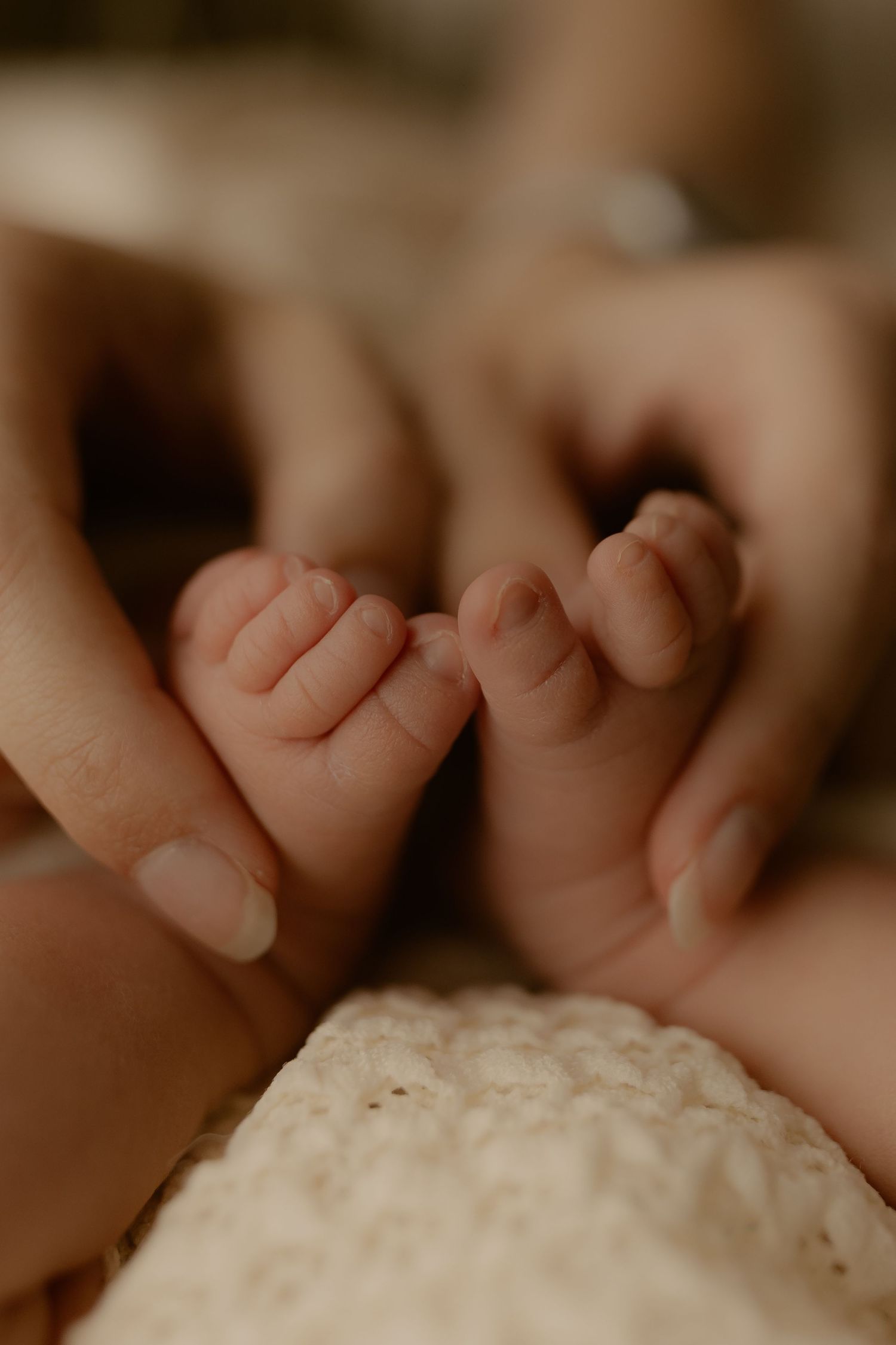 Newborn baby feet resting on textured white blanket.
