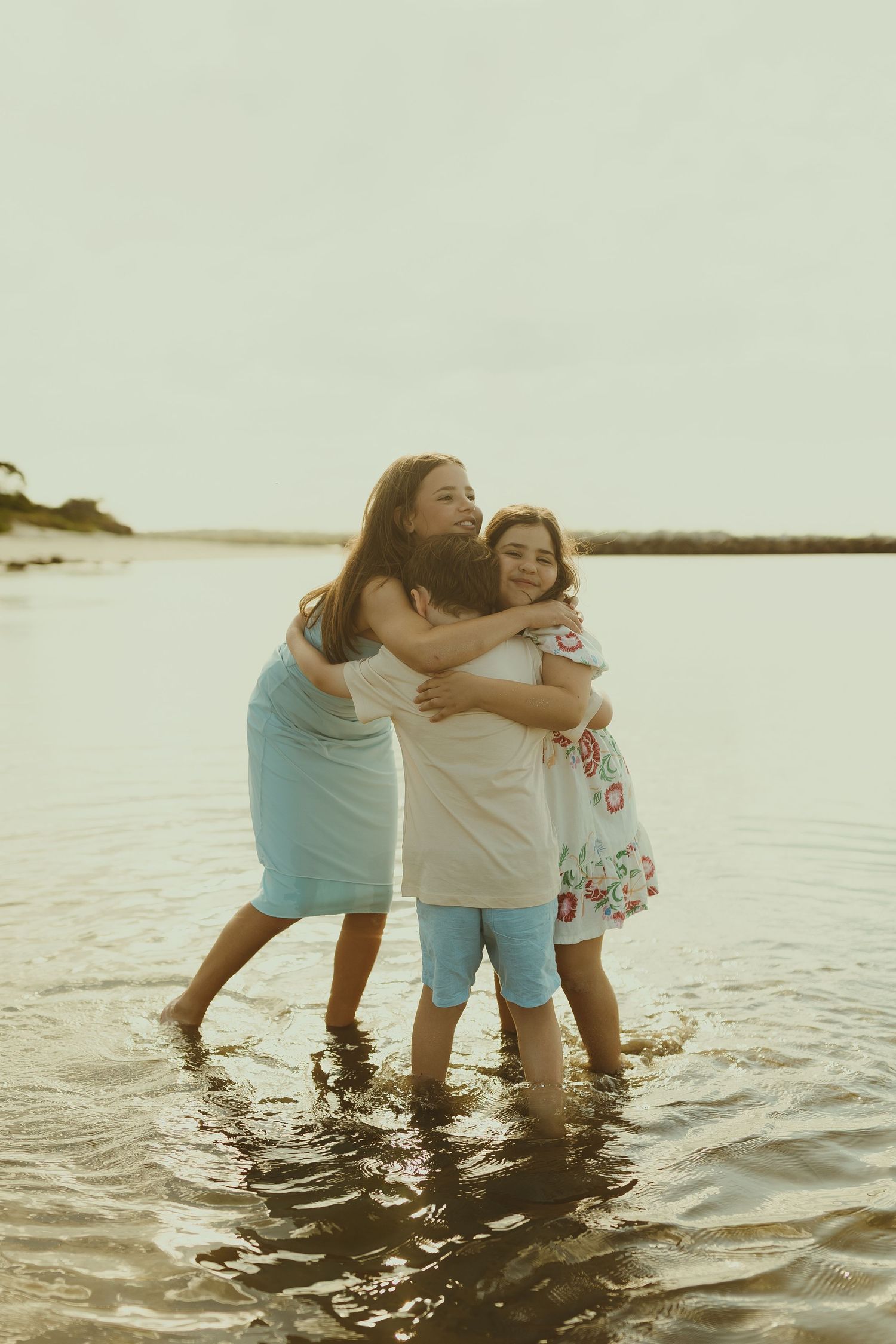 Group enjoying quality time together while wading in shallow ocean waters at sunset.