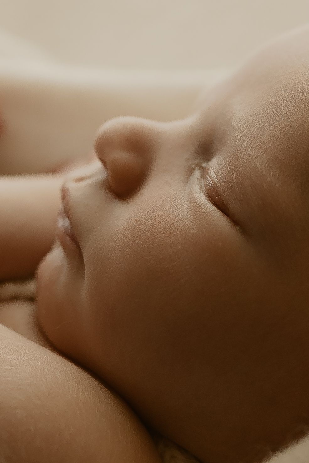 A sleeping baby captured in a peaceful moment with soft natural lighting and smooth skin tones in sepia.