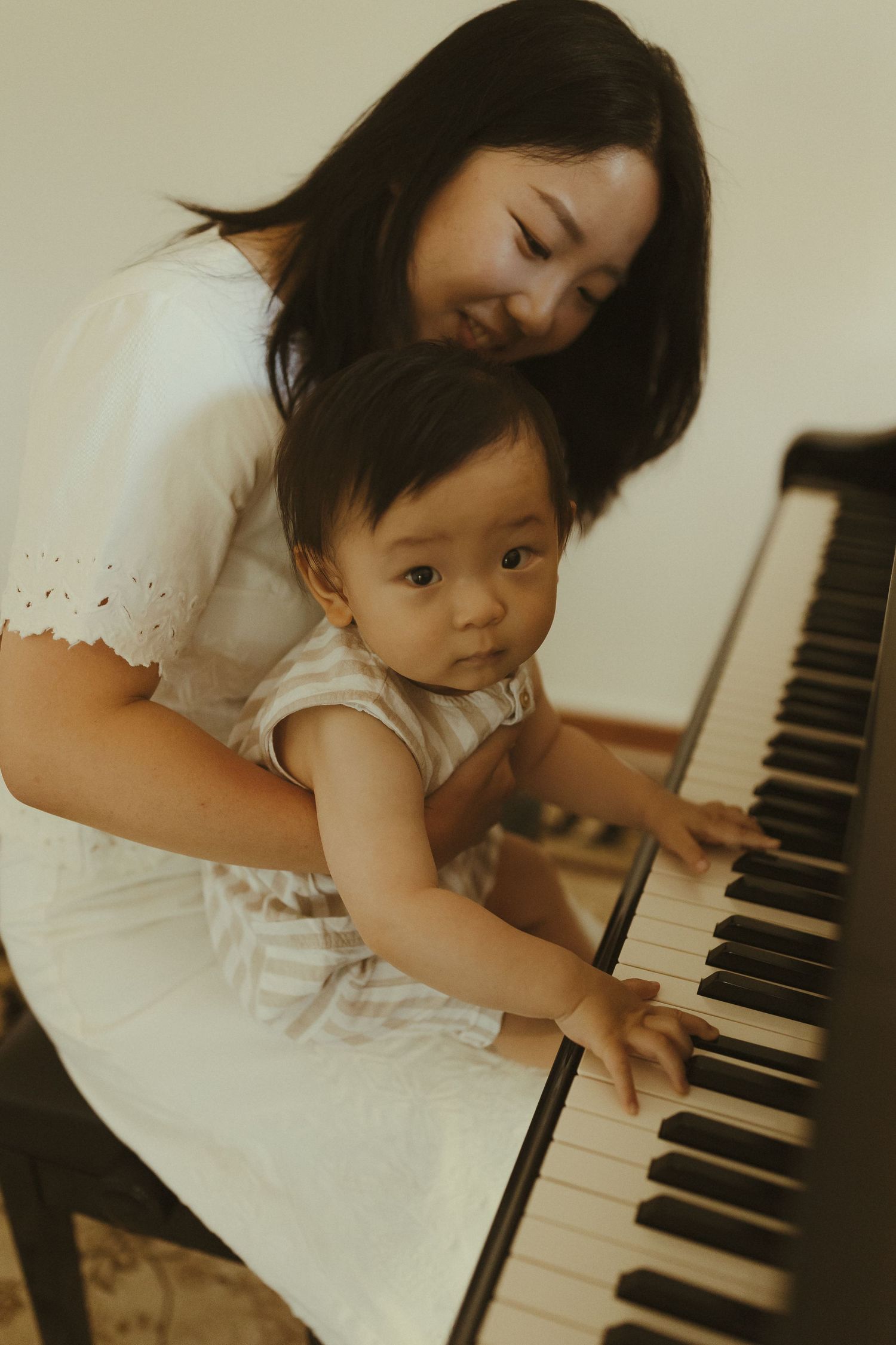 Two people share a moment at the piano, exploring music together.
