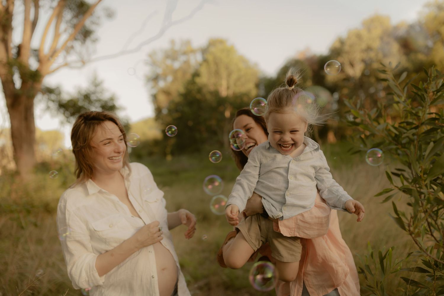 A magical outdoor moment with bubbles floating in golden sunlight during a sunset photo session in nature.