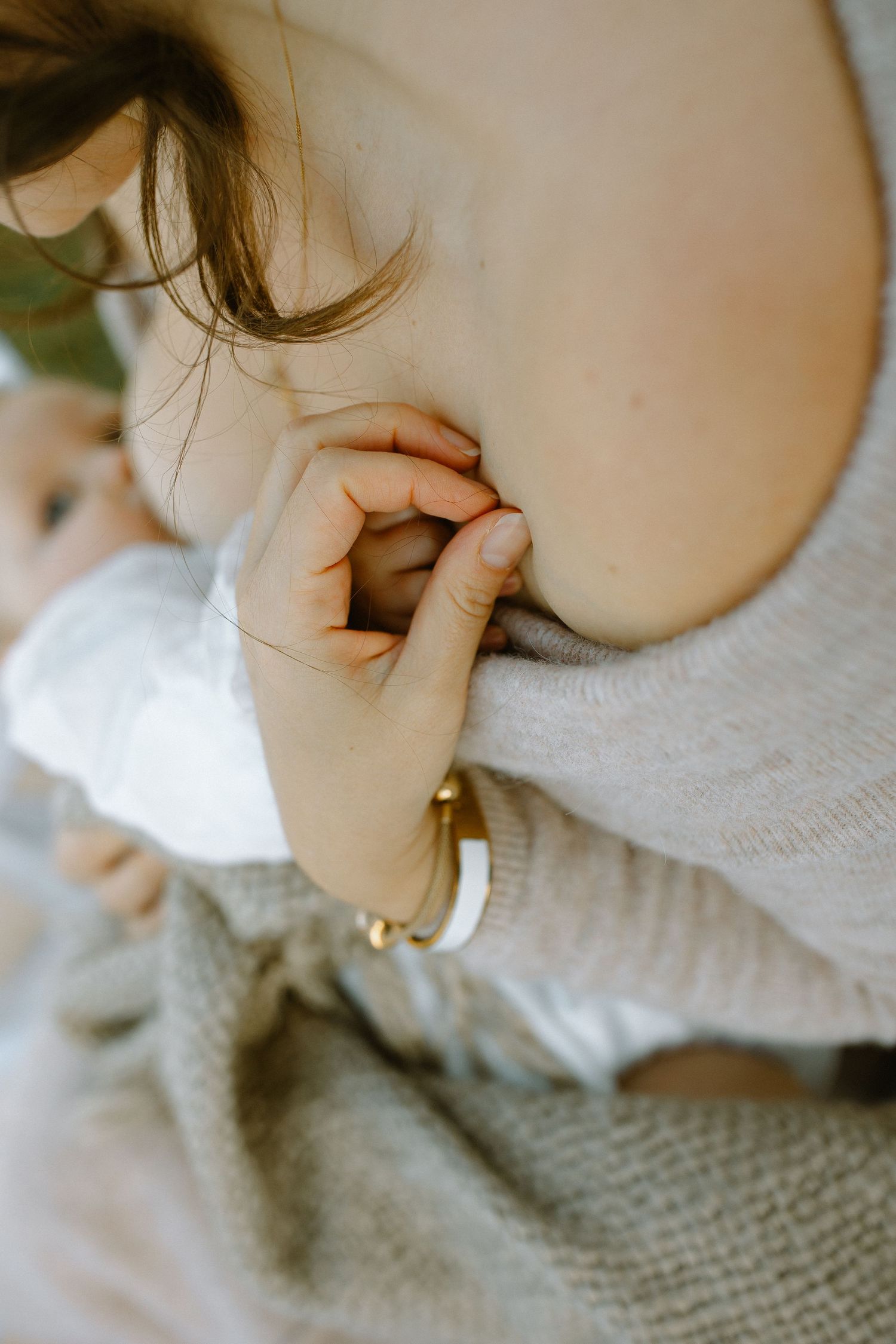 Close-up shot of a baby's tiny hand grasping a finger adorned with a gold ring.