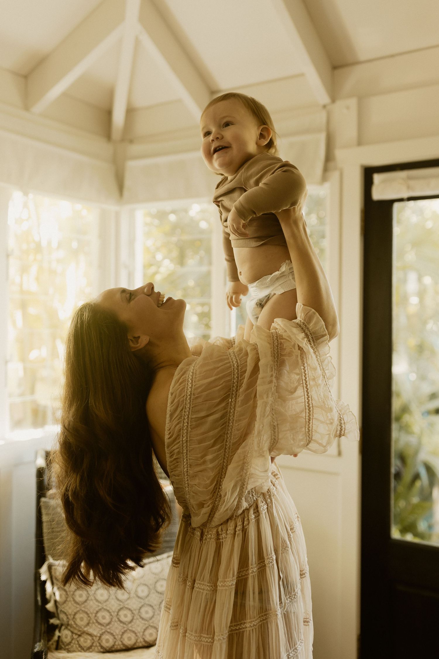Joyful bonding moment in sunlit room with white vaulted ceilings and large windows.