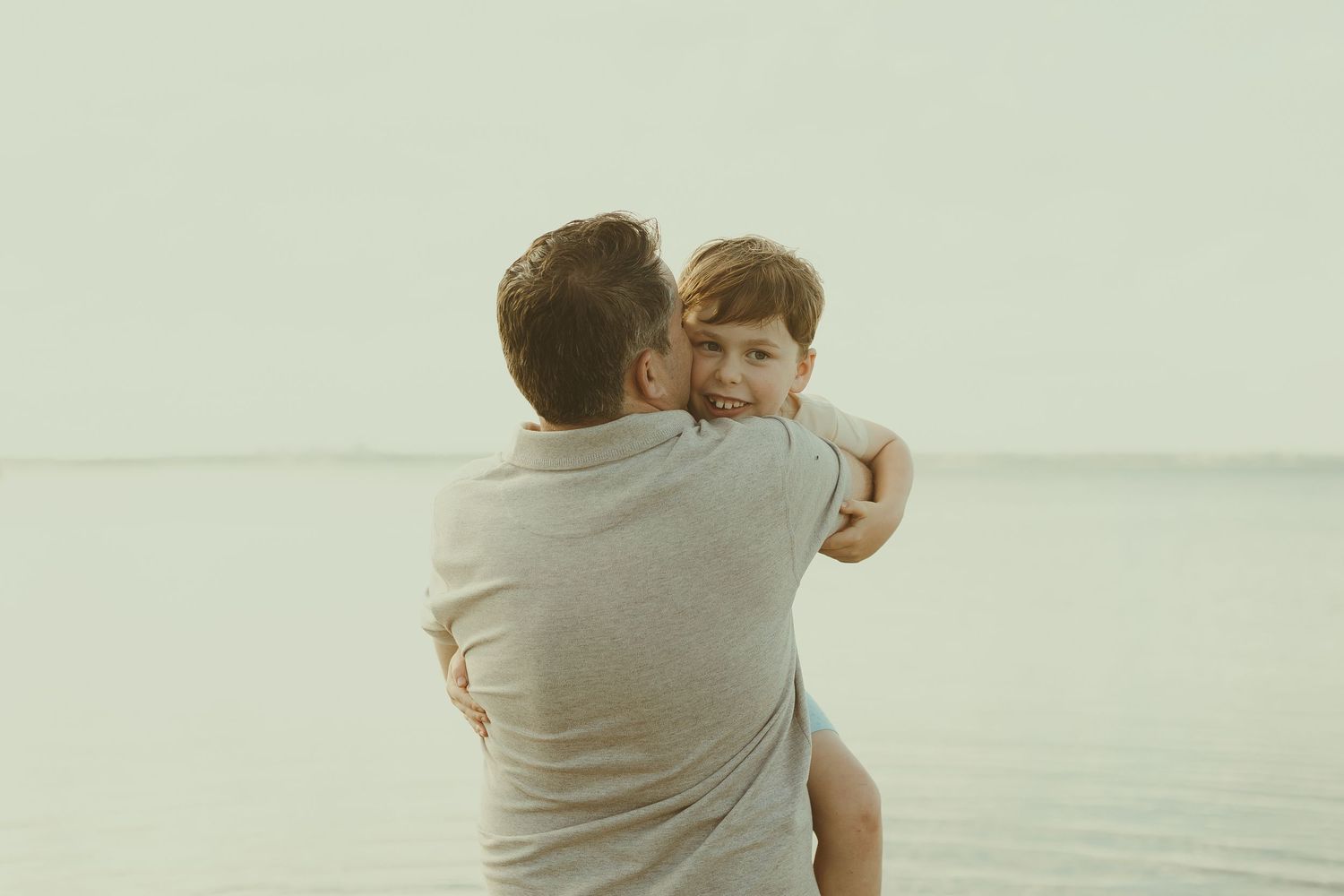Family members embrace while enjoying a peaceful moment on the shoreline.