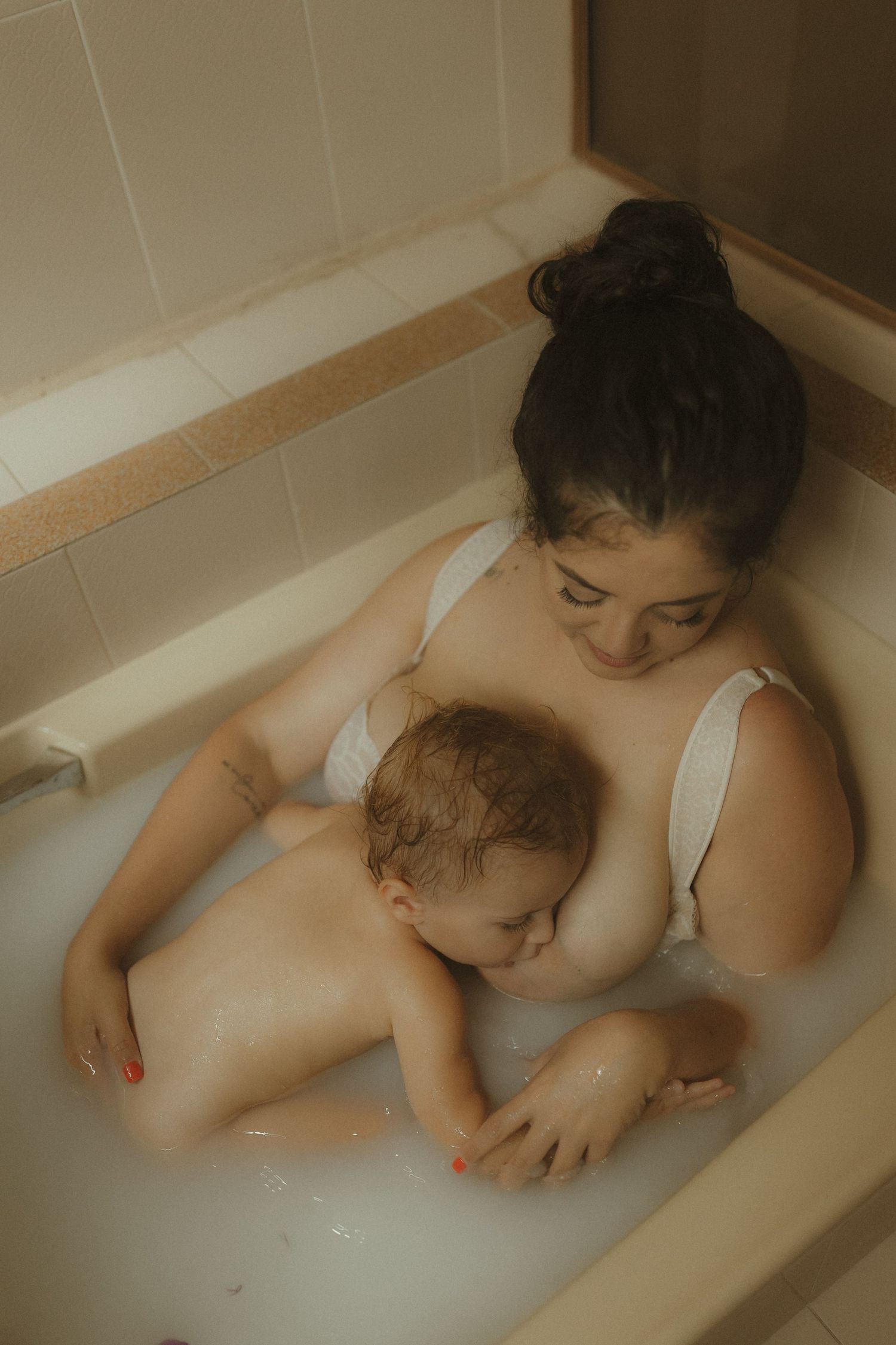 Intimate bathroom scene captures gentle bonding between parent and child in a bathtub.