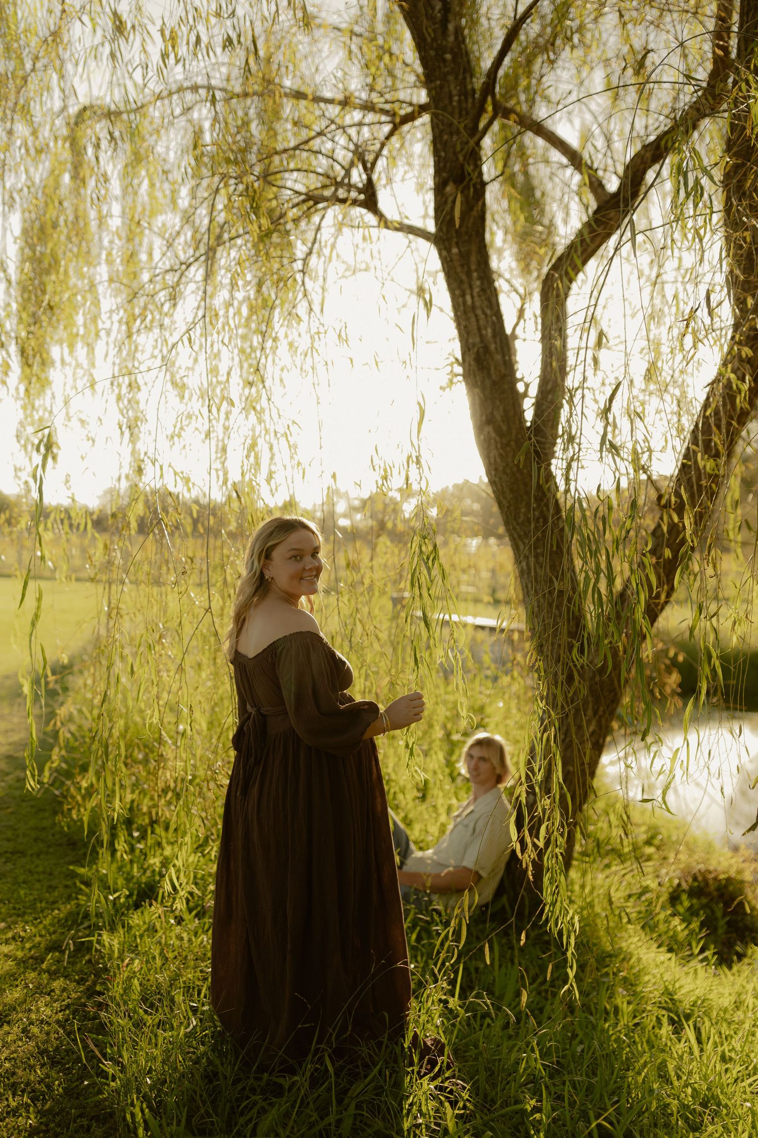 Willow trees frame a peaceful lakeside scene during golden hour.