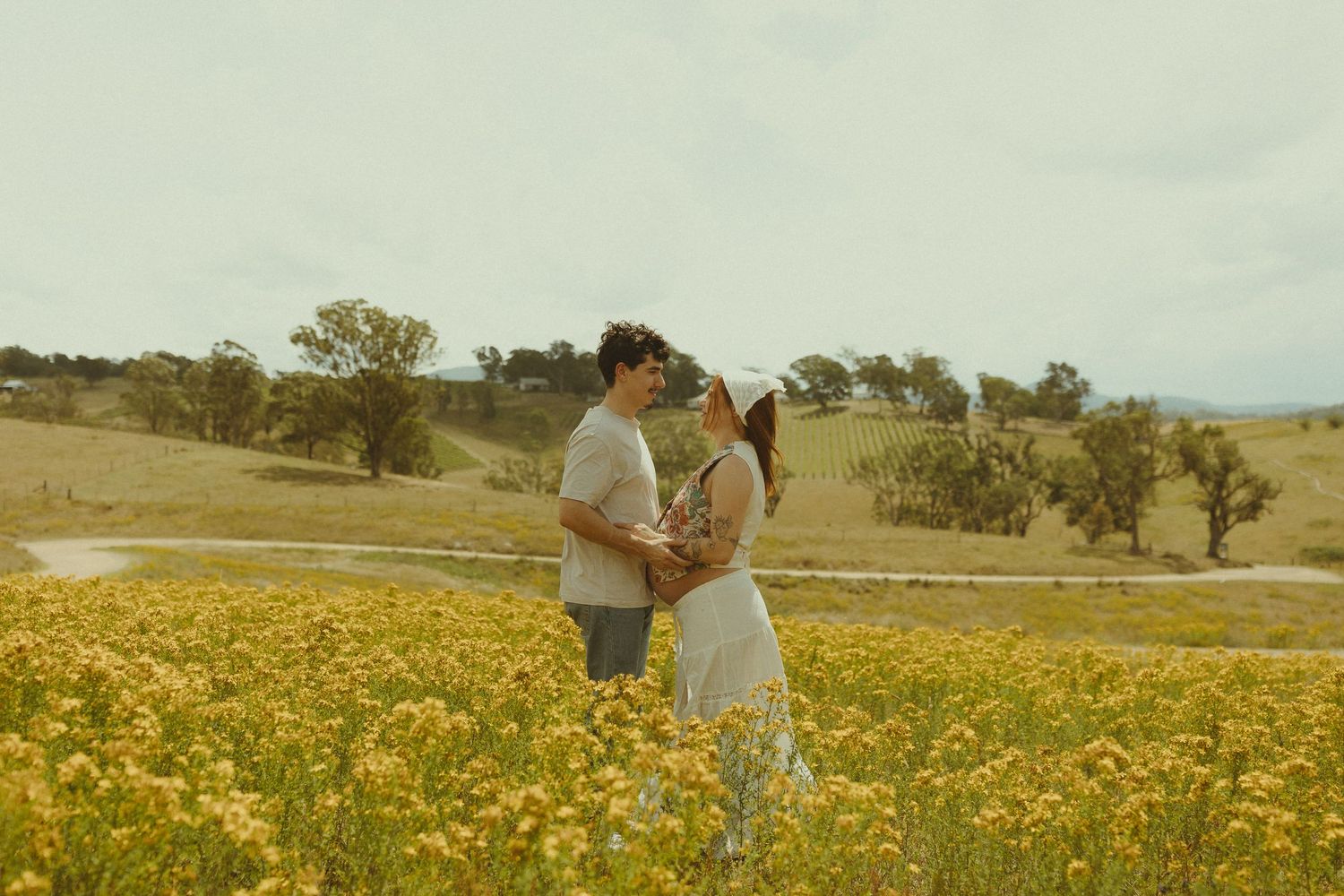 A romantic moment captured in a vibrant yellow wildflower meadow with rolling hills in the distance.