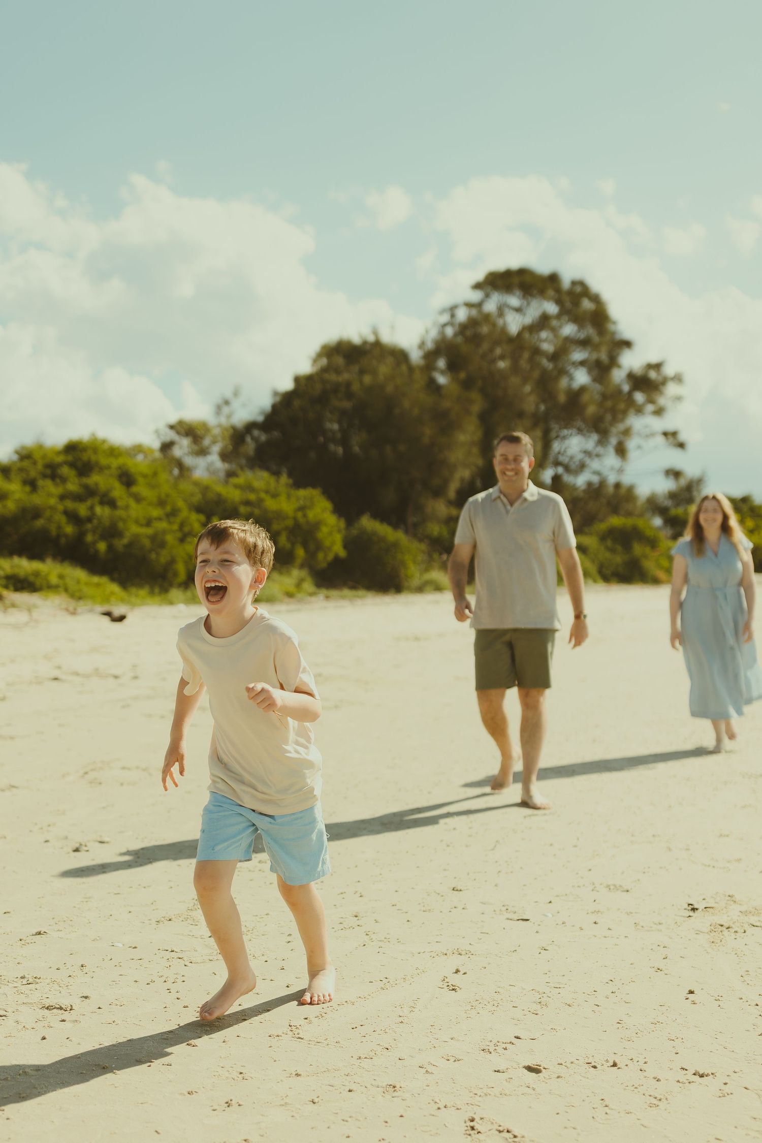 People running and playing together on a beautiful sandy beach during a bright sunny day.