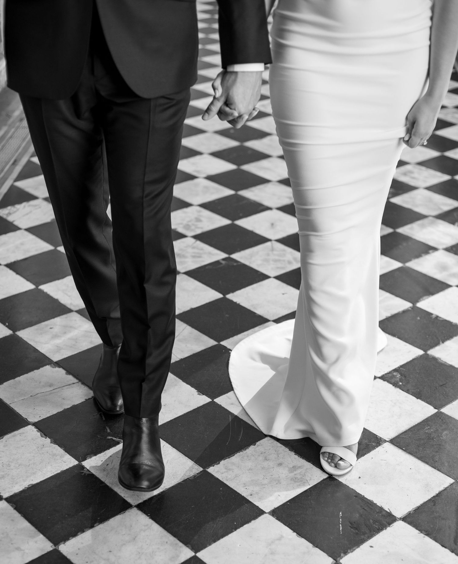 Black and white detail shot of formal attire on checkered ballroom floor.