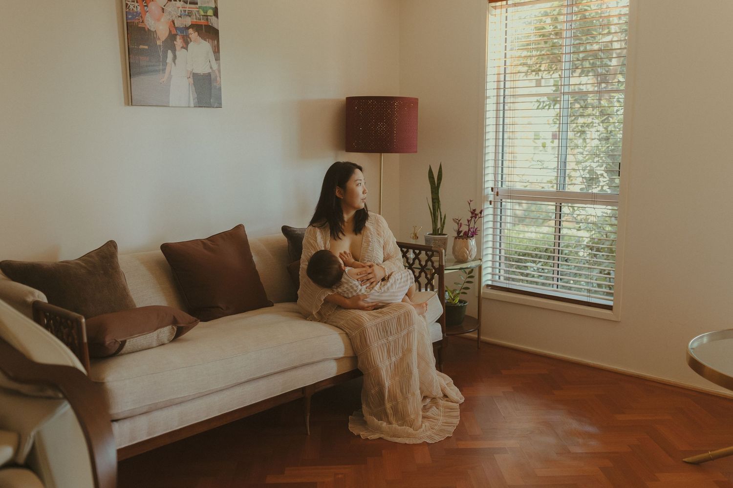 A cozy living room interior features a white sofa, wooden floors, and natural light streaming through windows.