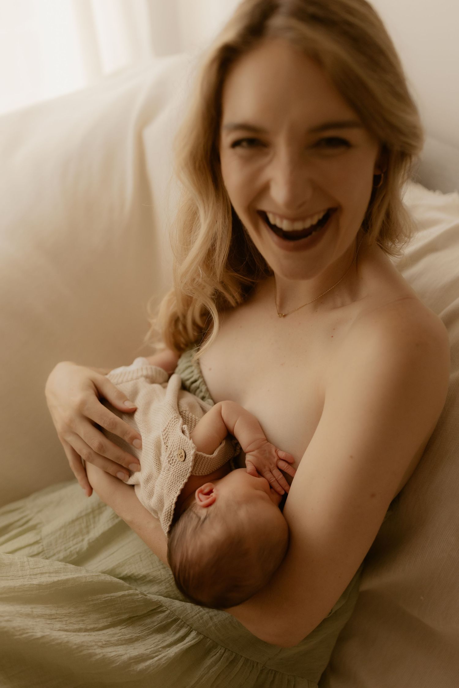 Intimate motherhood moment with newborn in soft natural light.