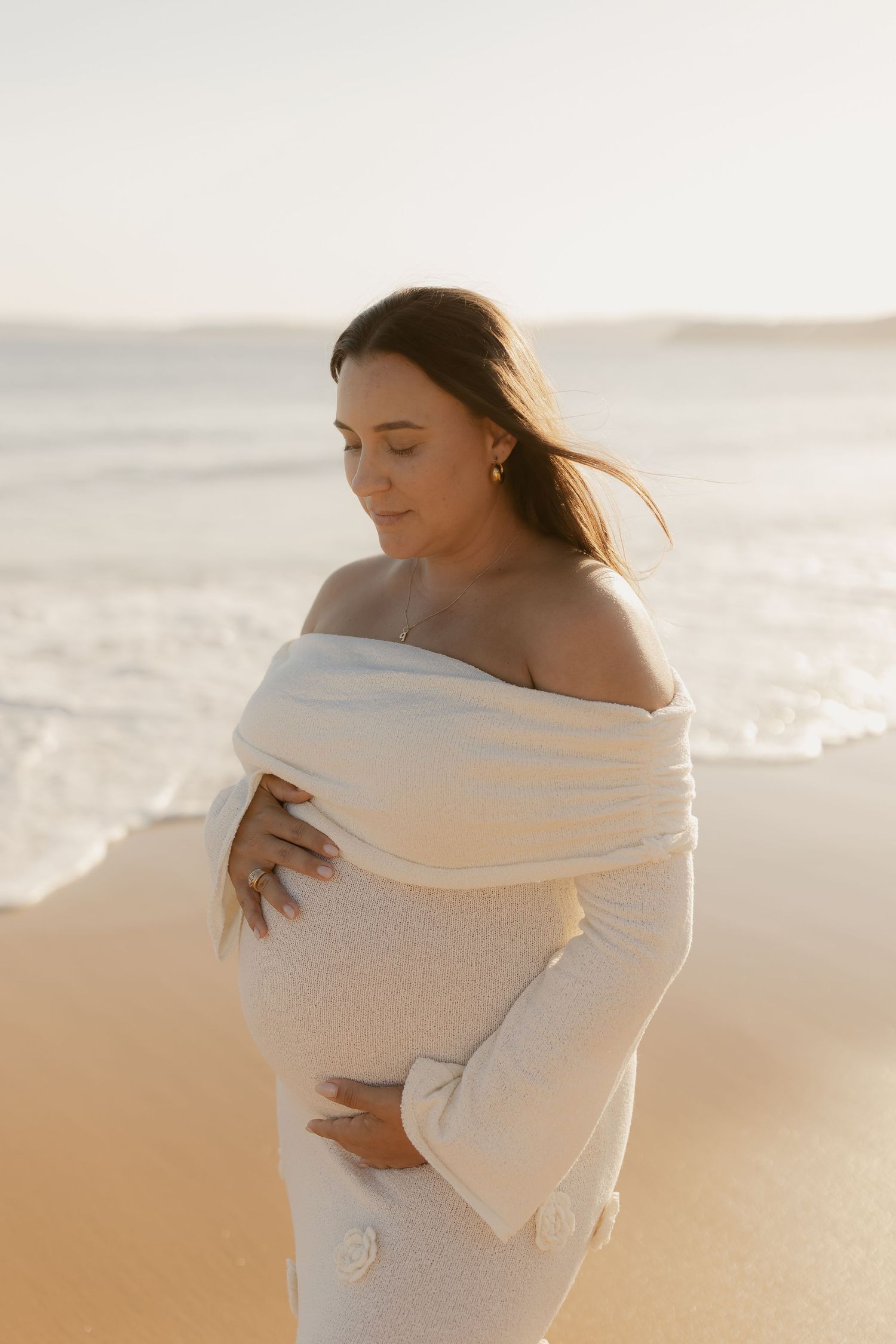 A tender embrace captured in soft light on a peaceful beach at sunset.