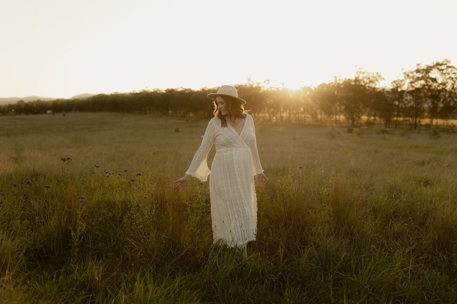 White flowy dress billows in the wind across a sun-drenched meadow at golden hour.