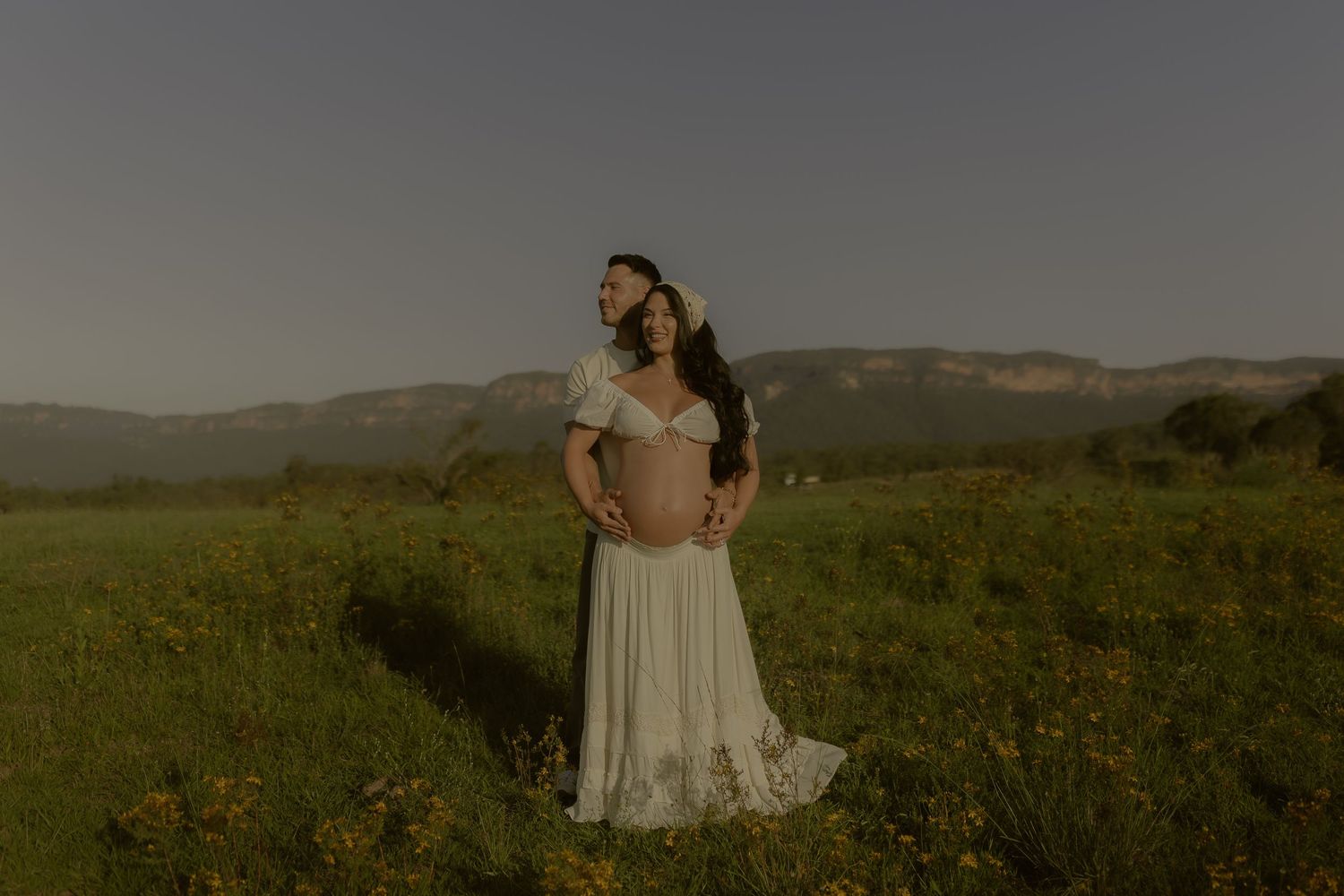 Ethereal scene of a white dress flowing in the breeze against a mountainous landscape at dusk.