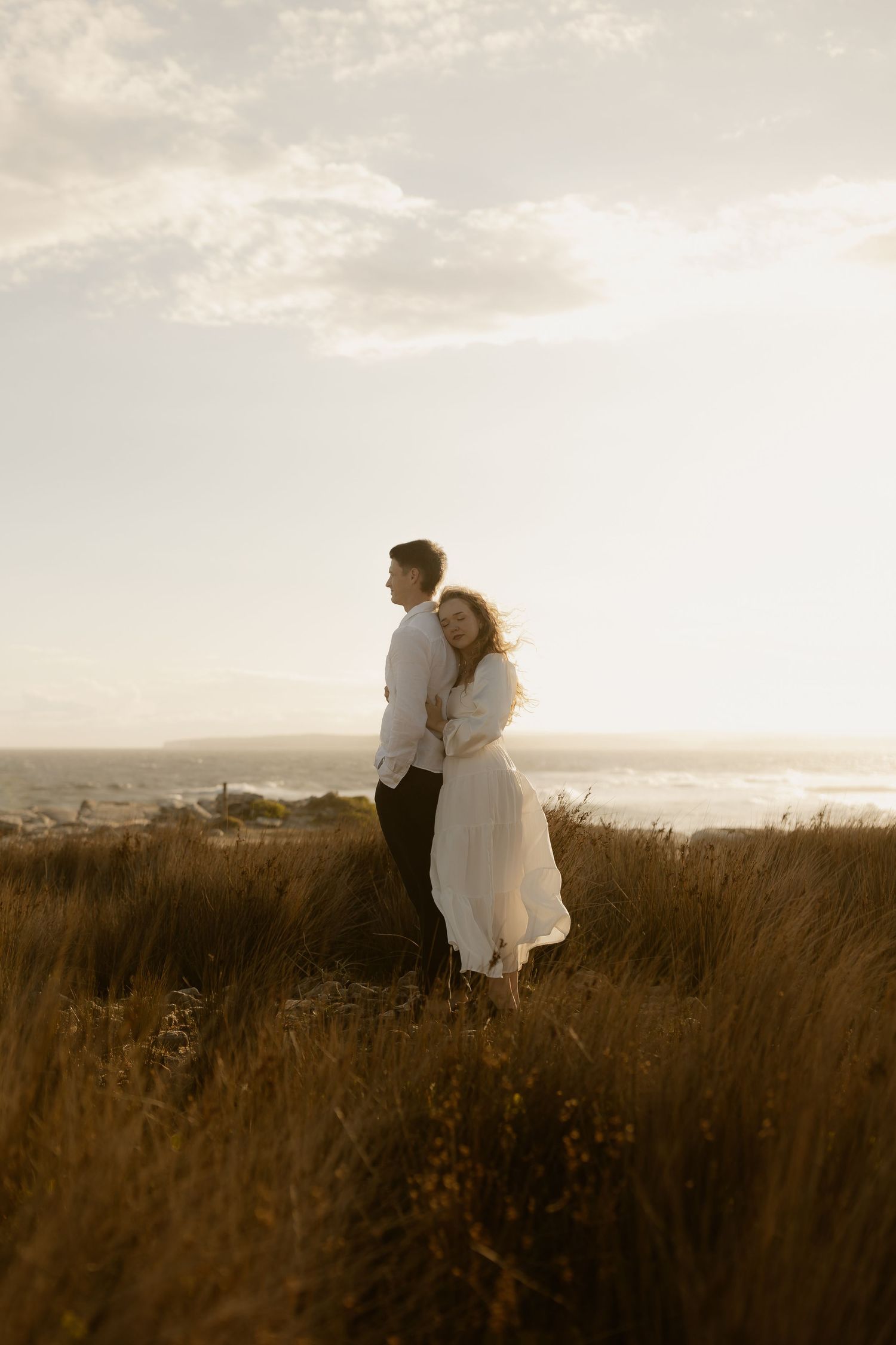 A romantic couple stands in a field at sunset, their silhouettes captured in a series of dreamy golden-hour moments.