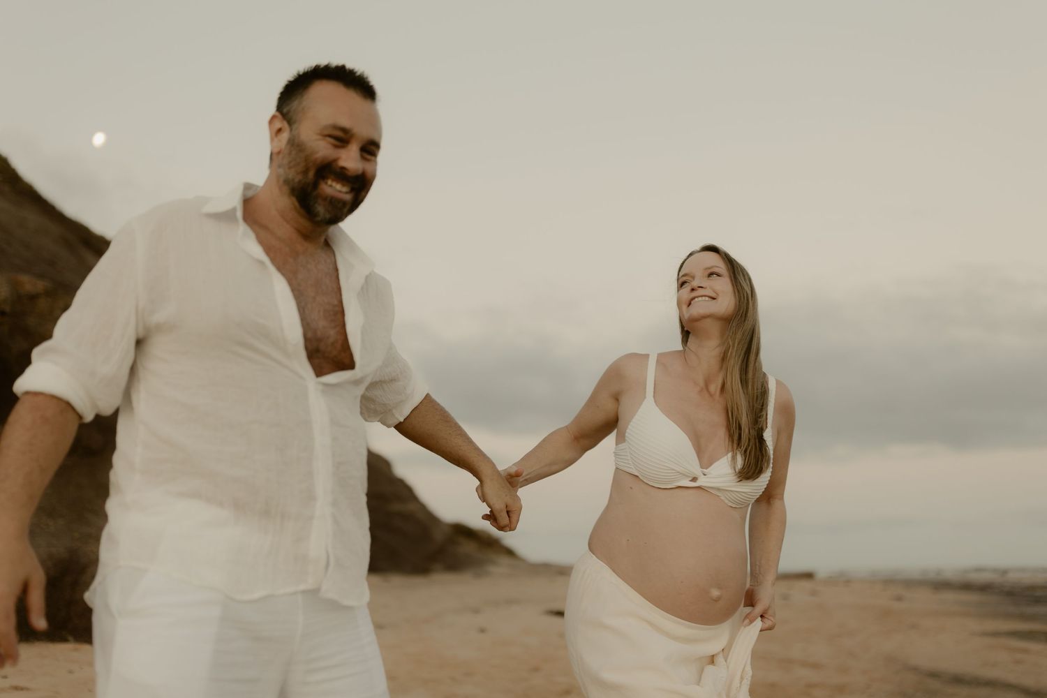 A couple shares intimate moments while walking along a beach at sunset.