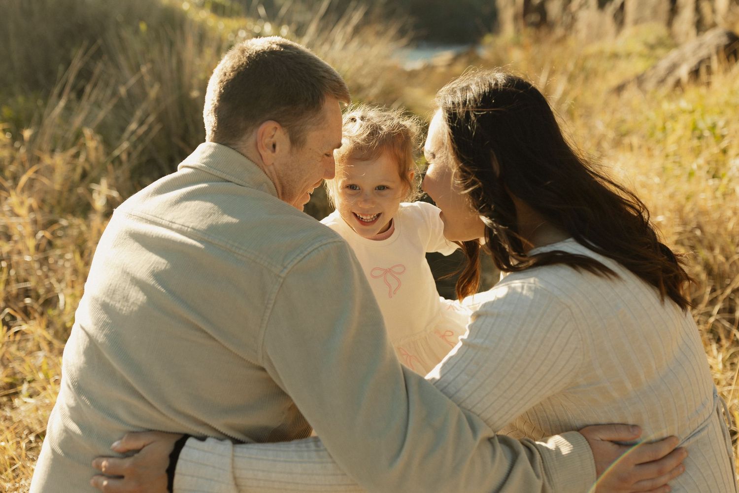 Intimate family moment shared on a scenic trail with golden sunlight filtering through.