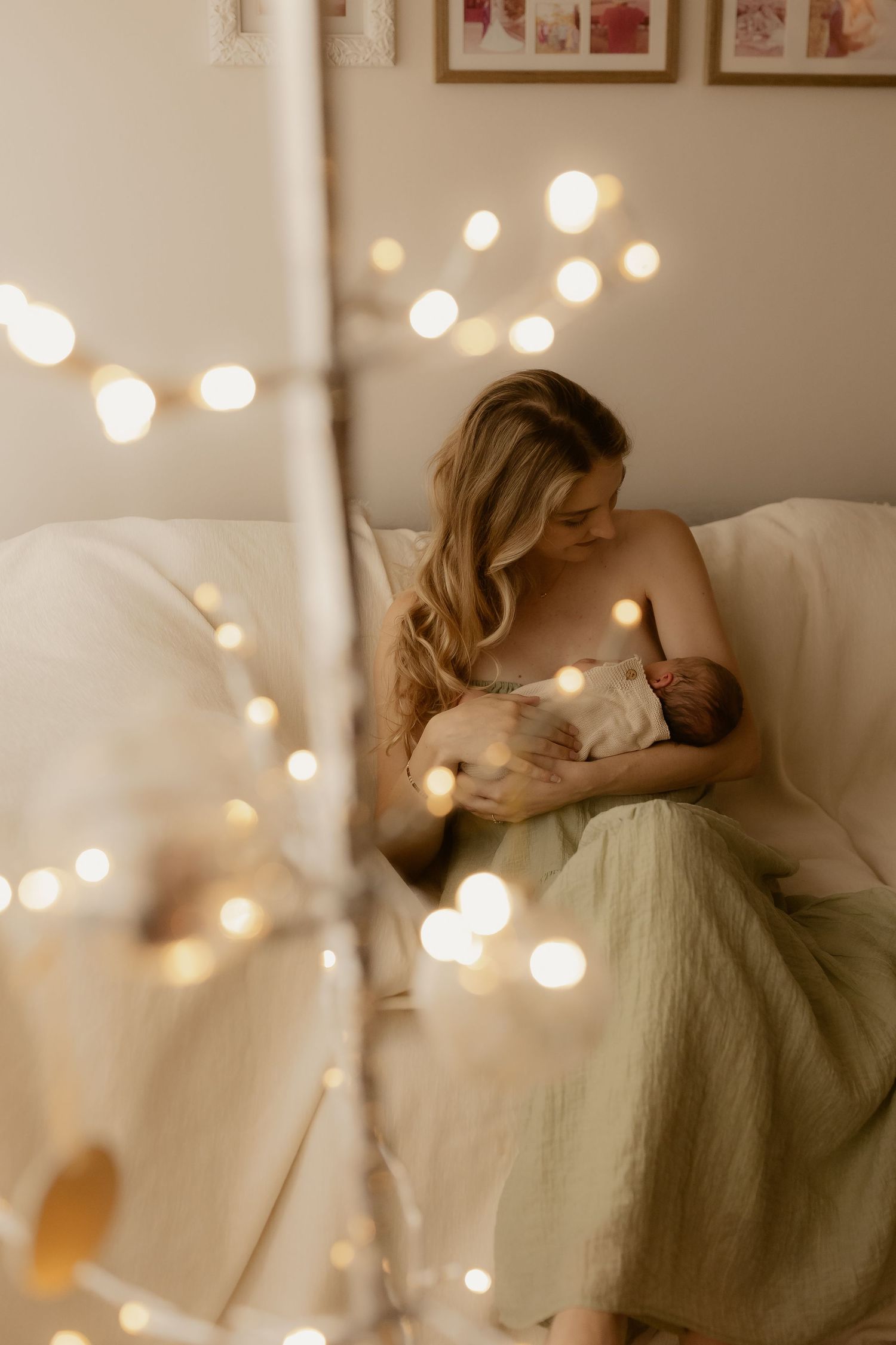Cozy nursery scene with string lights illuminating tender moment with newborn.
