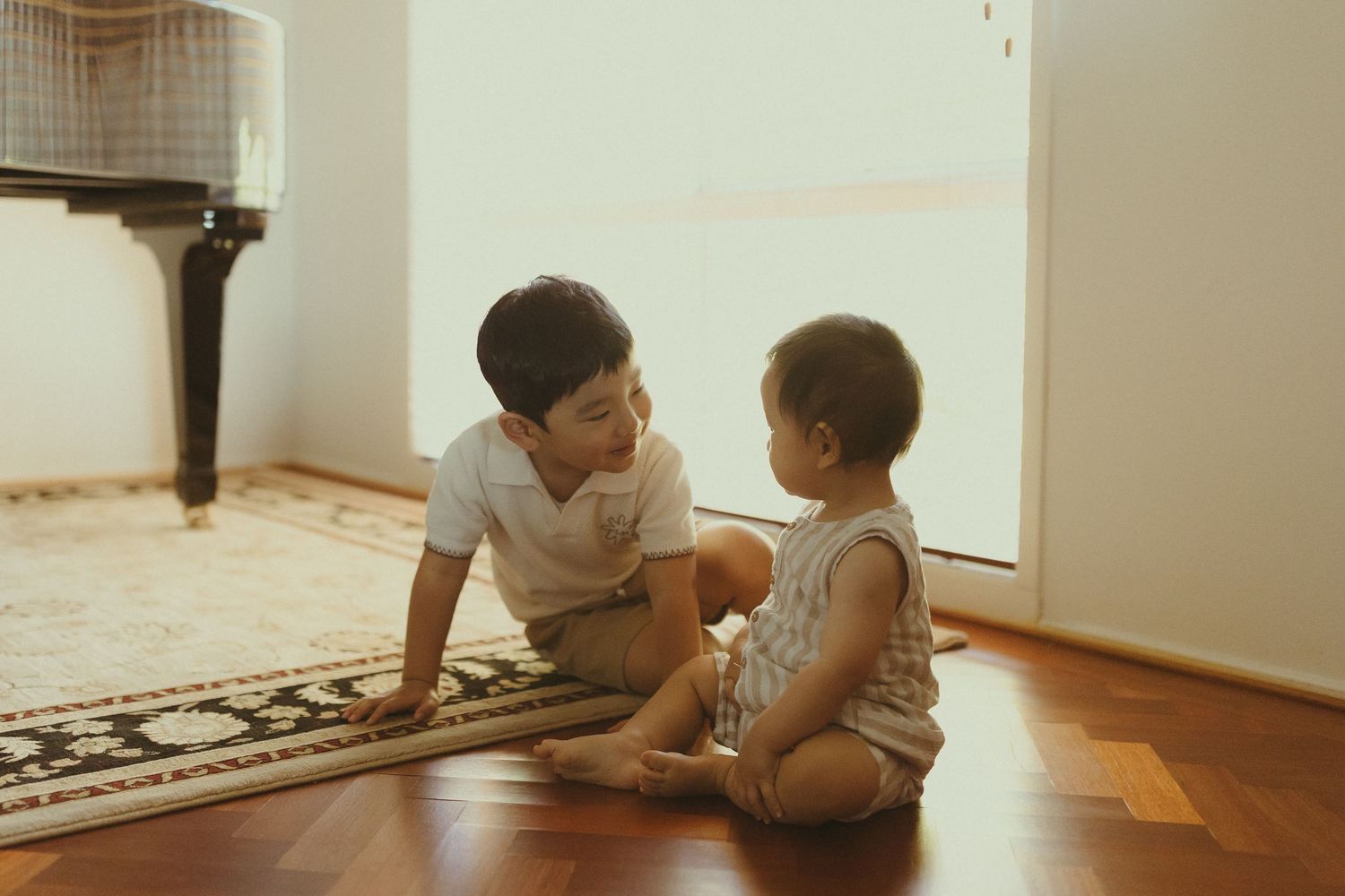 A tender moment shared between people lying on the floor in sunlit room.