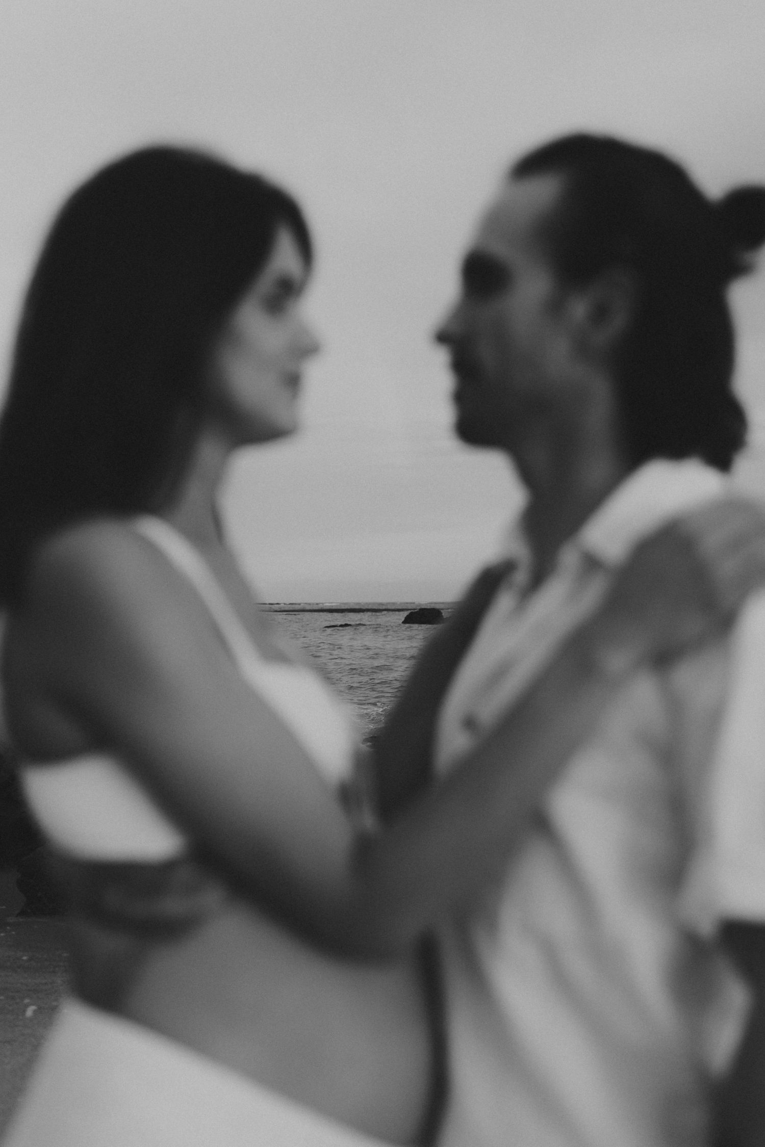 A romantic couple shares intimate moments in black and white silhouettes by the water.