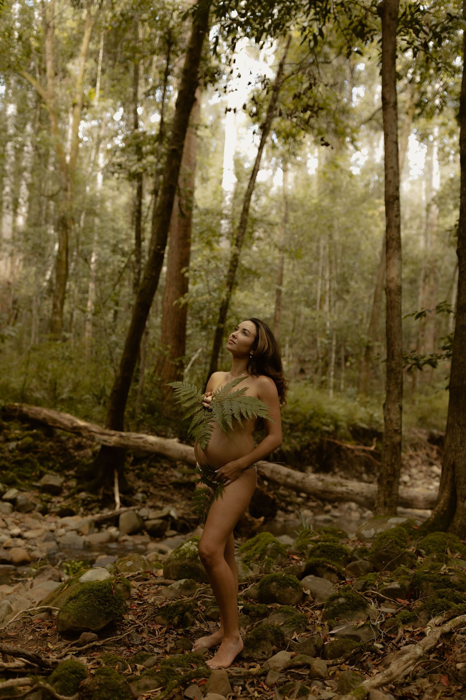 A dreamy forest photography session showcasing ethereal poses amidst misty trees and rocky ground.