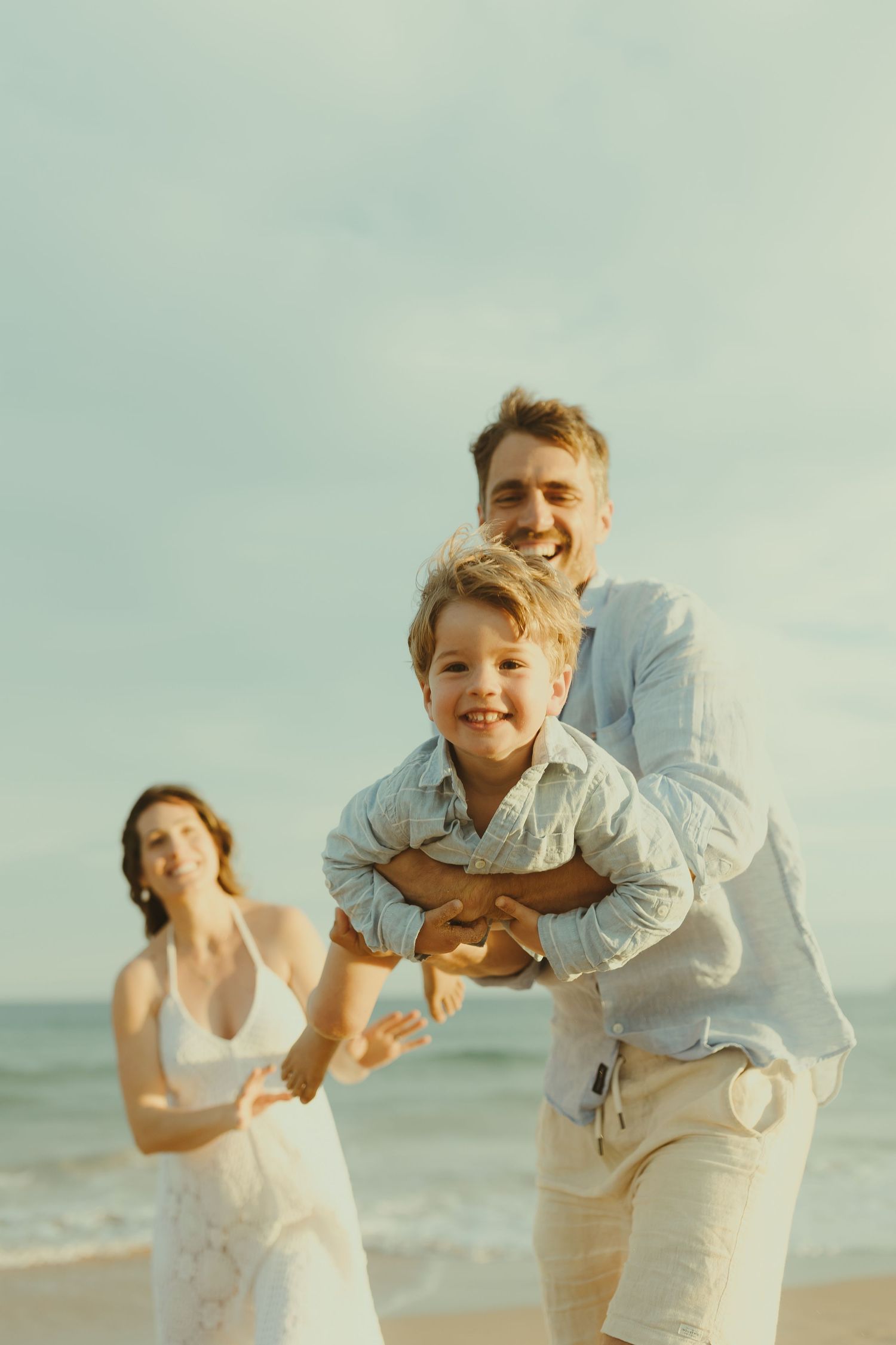 Candid family photos show laughter and fun during a beach photo session.