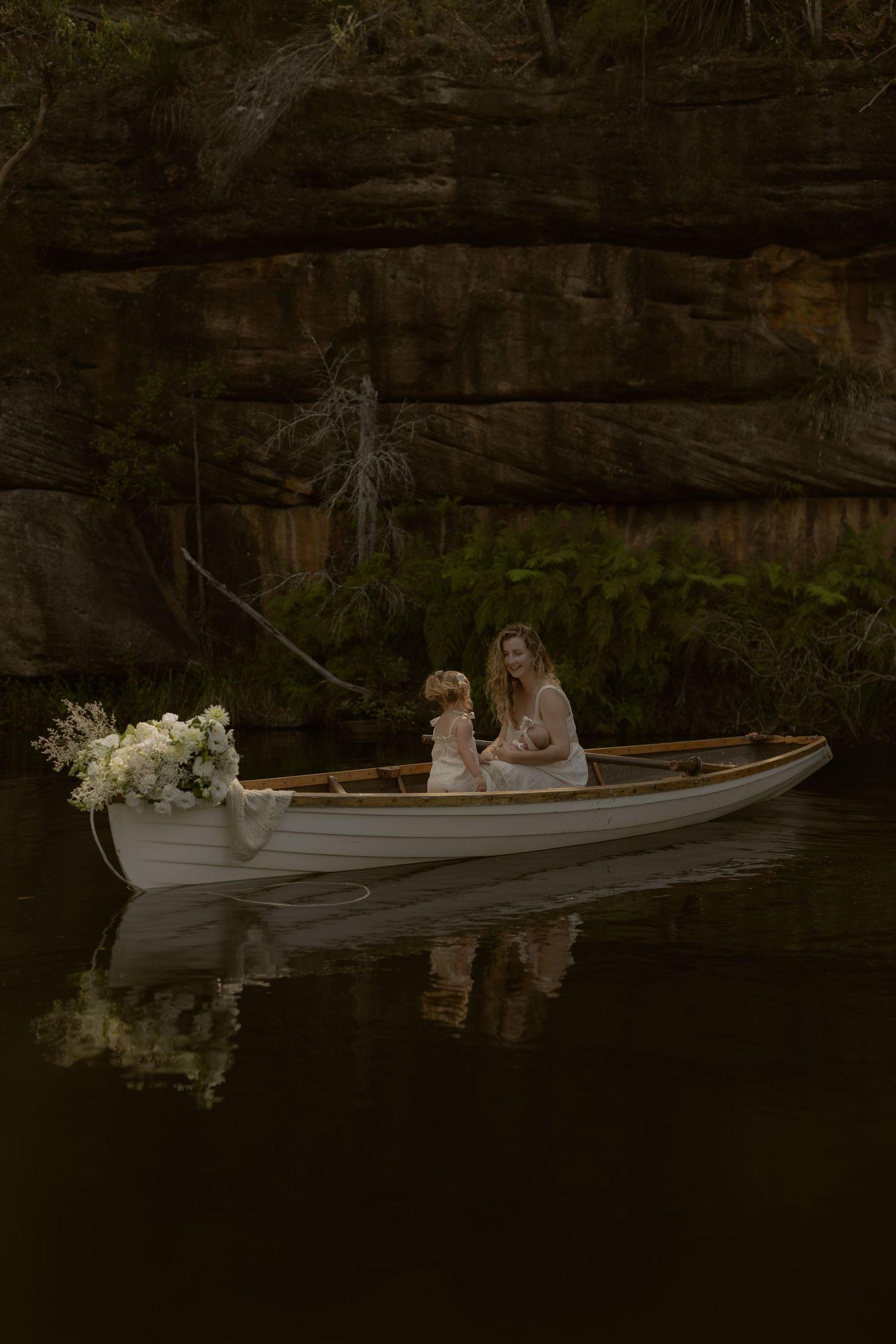 A romantic canoe ride on a serene lake with floral decorations and natural rock formations in the background.