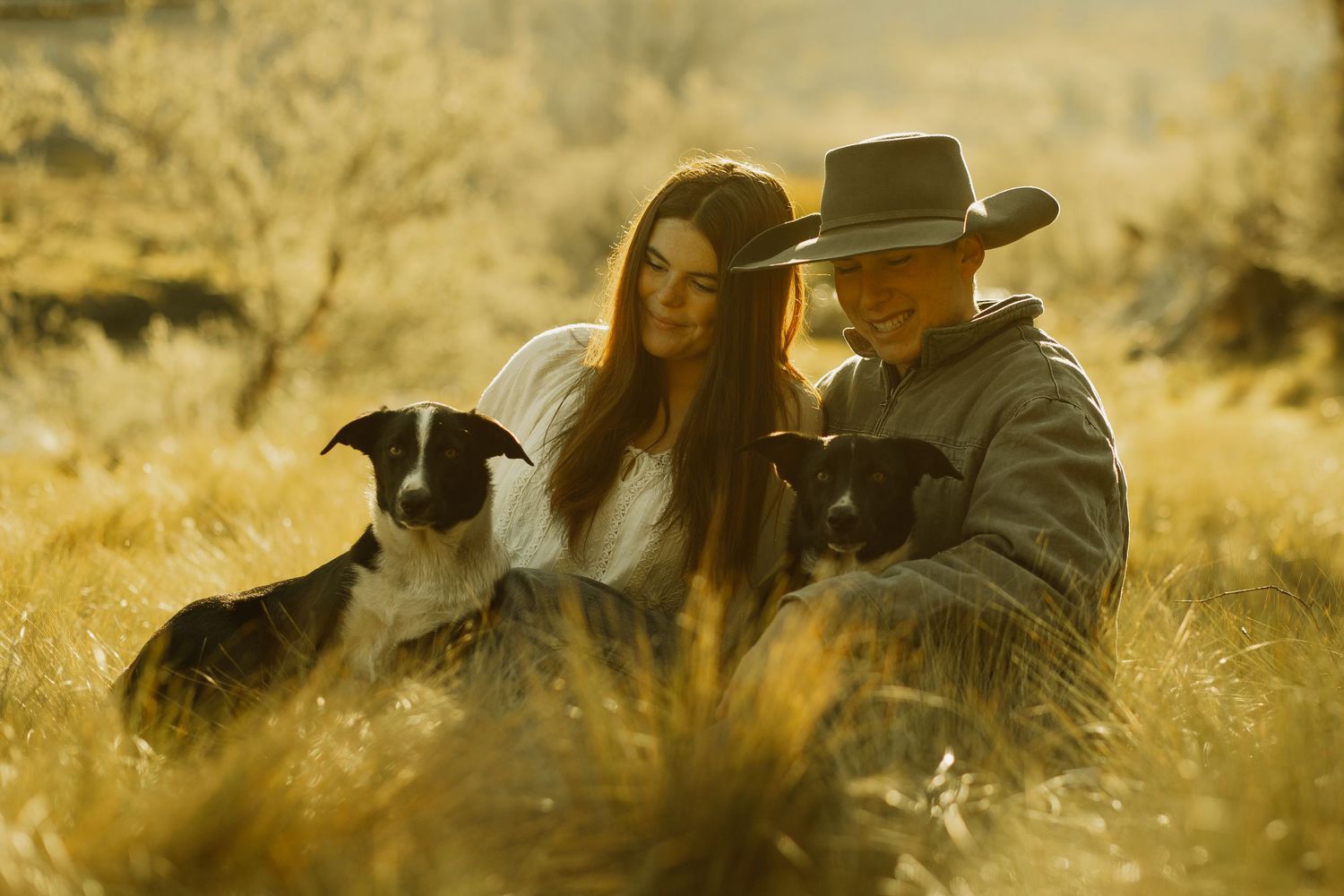 Romantic countryside scene with cowboy hats and horse silhouetted against golden sunlight.
