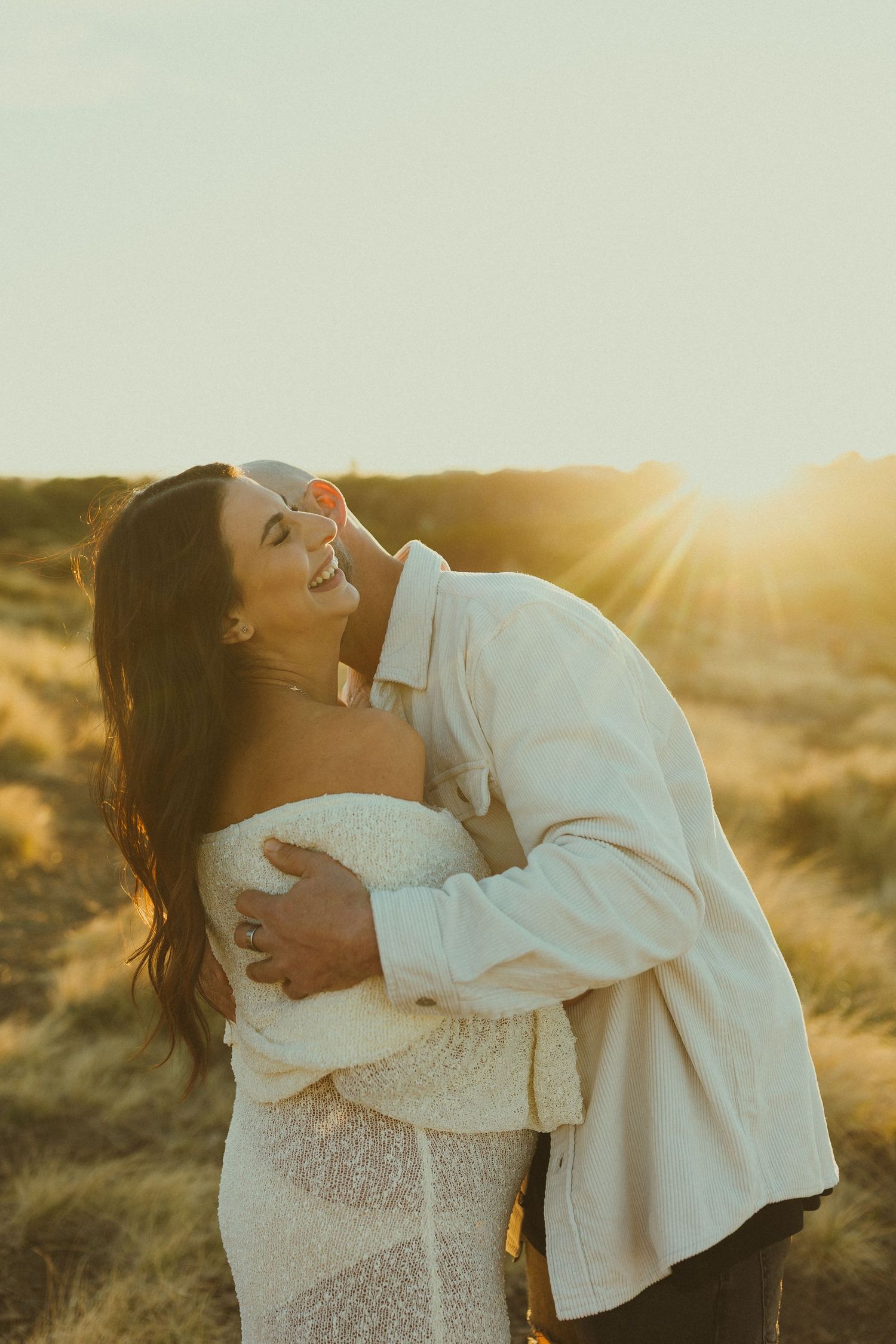 Intimate family moment captured in glowing golden sunlight against desert landscape.