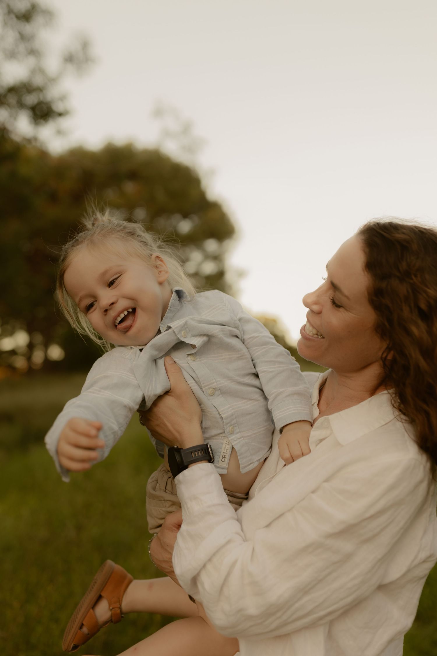 Candid moments of playful interaction between parent and child in a golden-hour field setting.