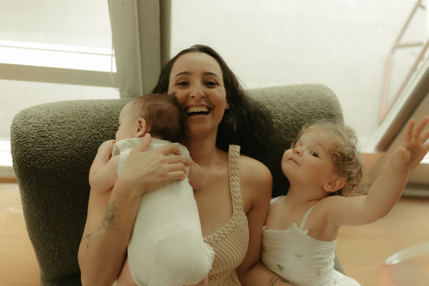 A heartwarming scene of laughter and play on a comfortable grey armchair.