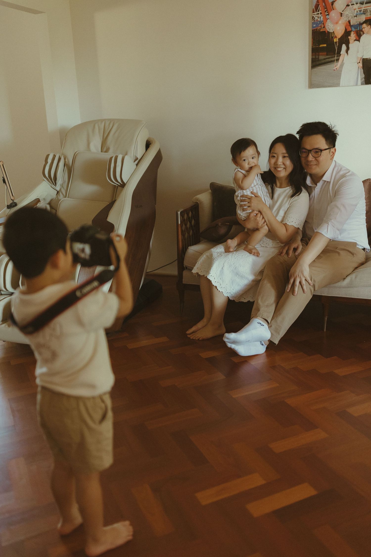 Family enjoying playful moments together on hardwood floors with decorative balloons.