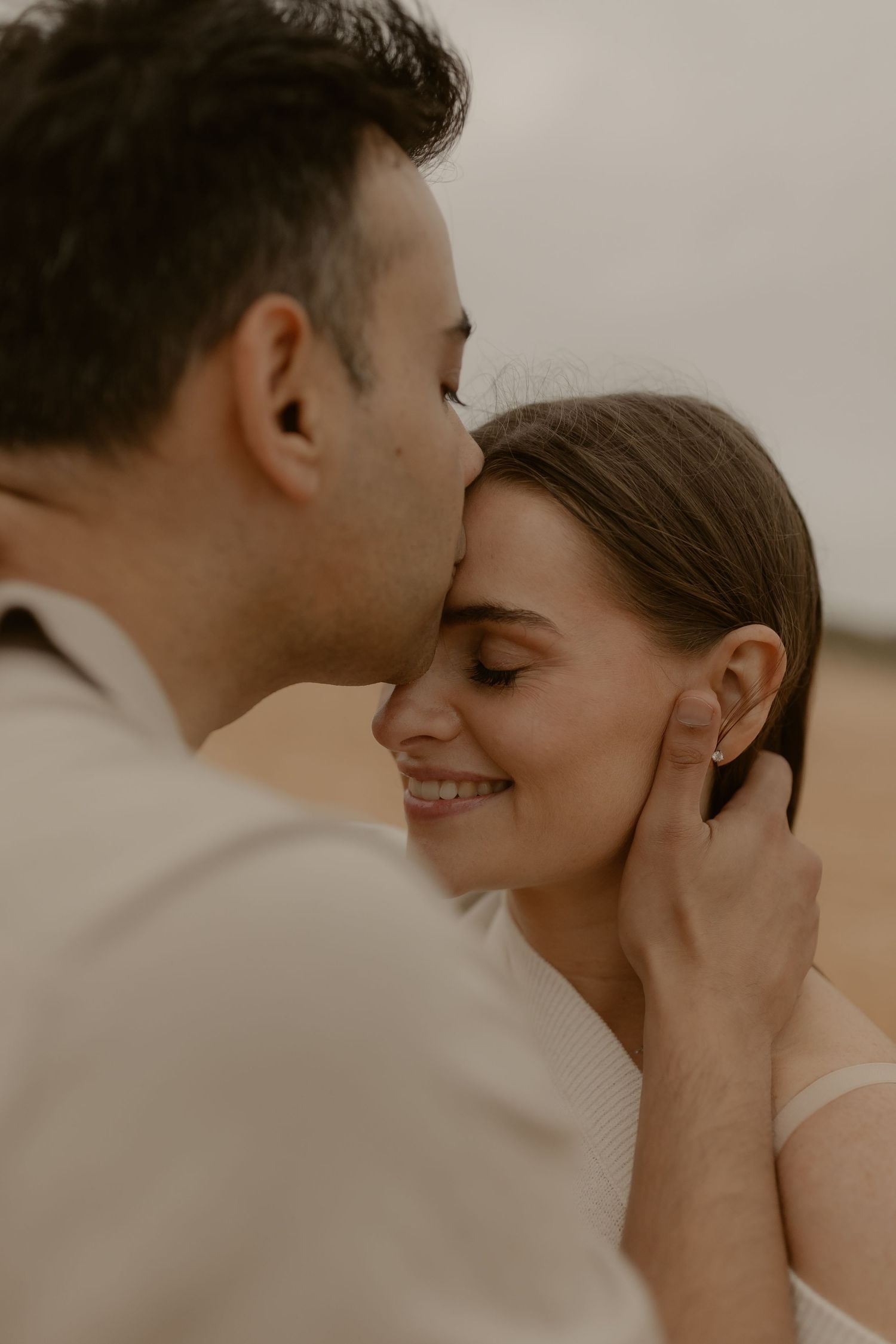 A tender romantic moment between a couple captured in warm sepia tones at sunset.