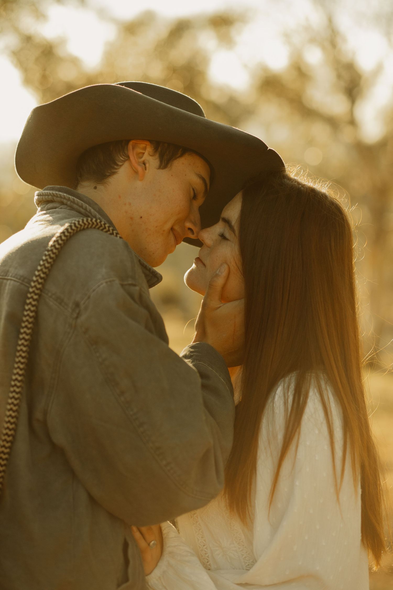 An intimate moment between couple in western wear captured in warm golden sunlight.