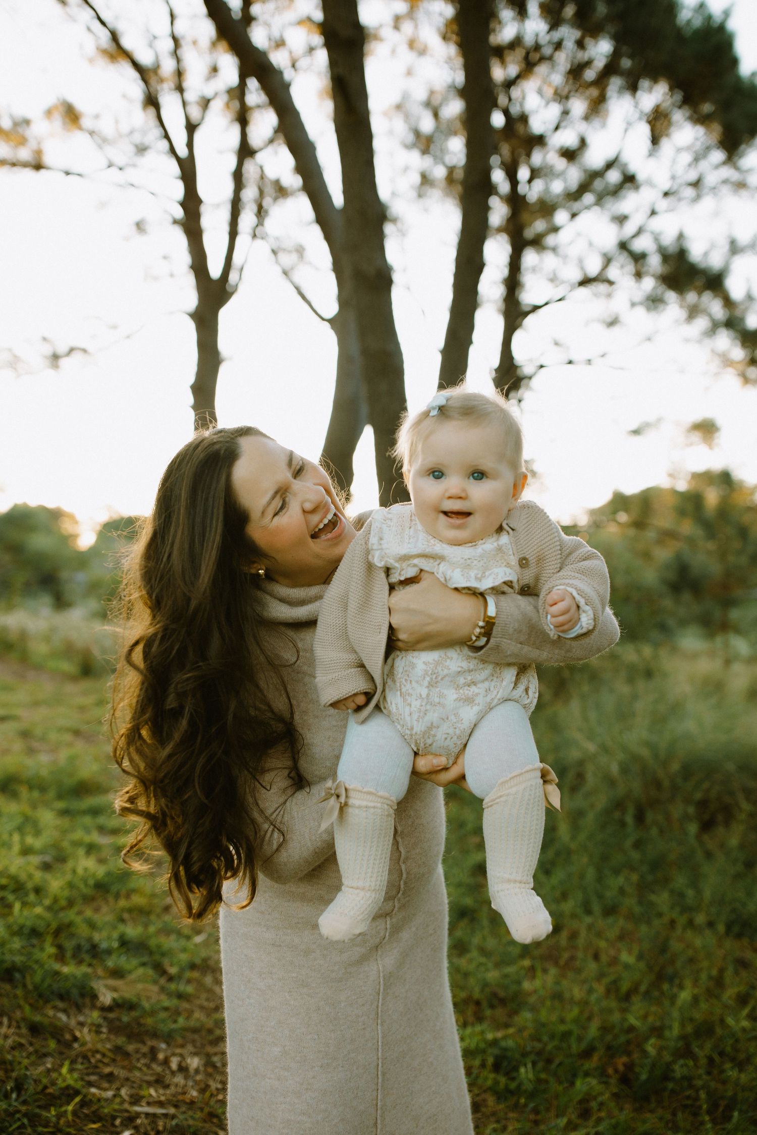 Mother and baby sharing joyful moment together in woodland setting with natural light.