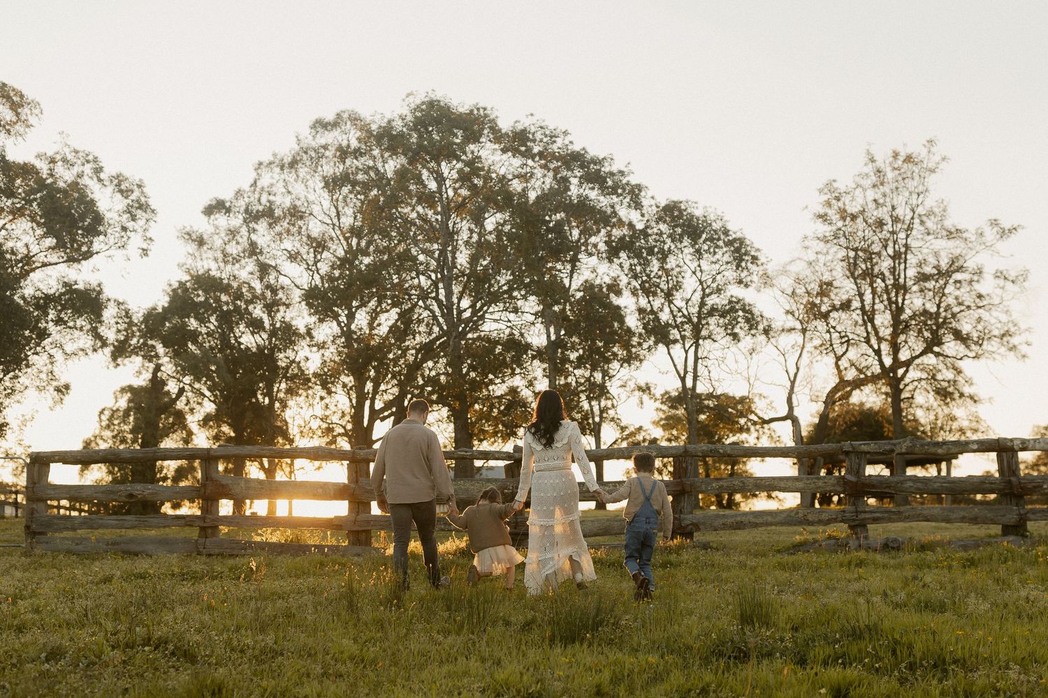 A panoramic view of silhouettes against a sunset in a rural field with trees in the background.
